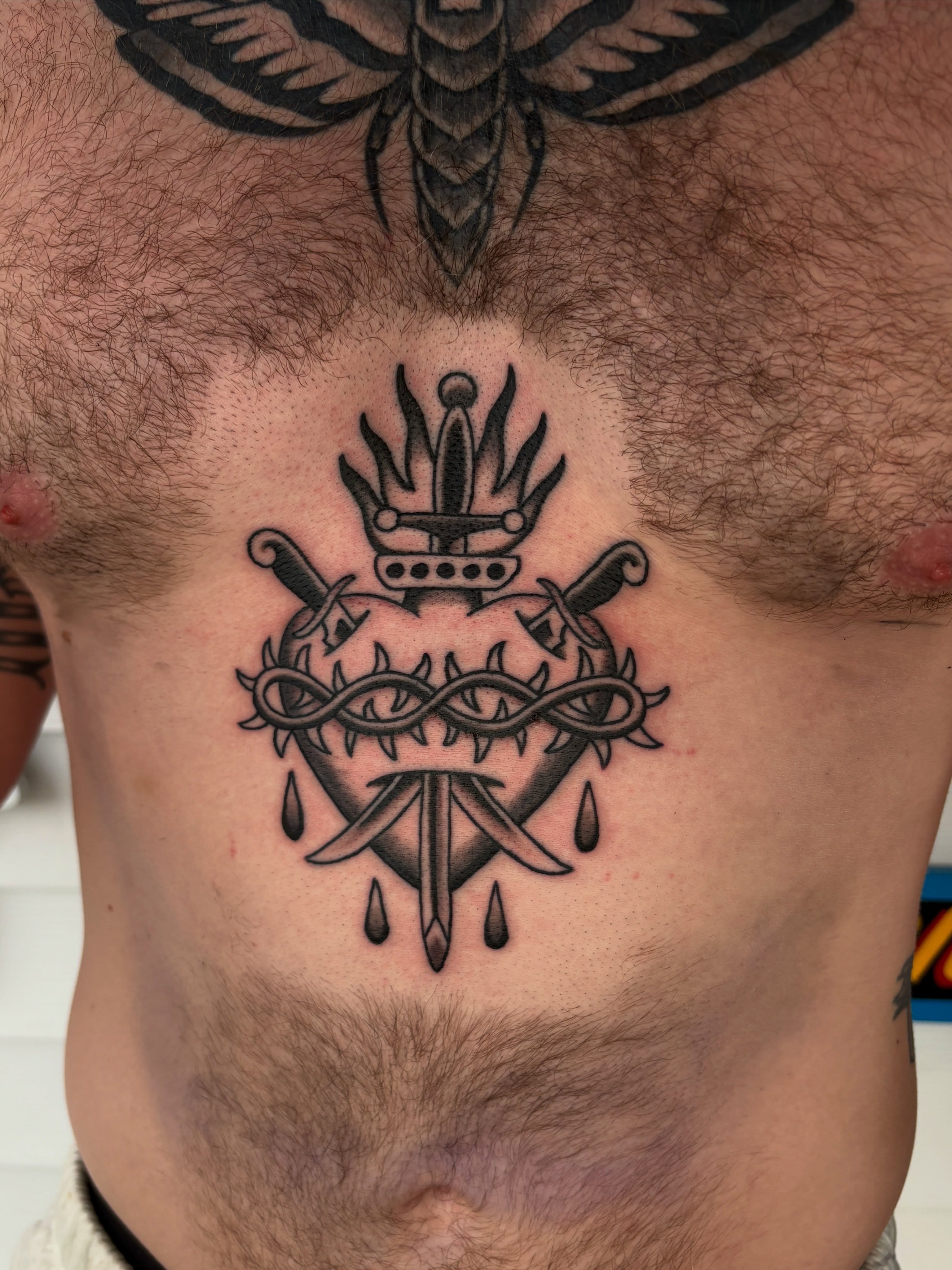 Heart with crown and swords geometric tattoo on the chest by Max Klapp, Austin, Texas