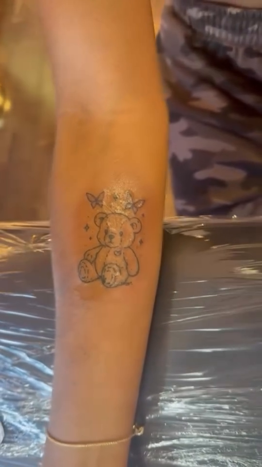 Teddy bear with flowers minimalist tattoo on the torso by Jay