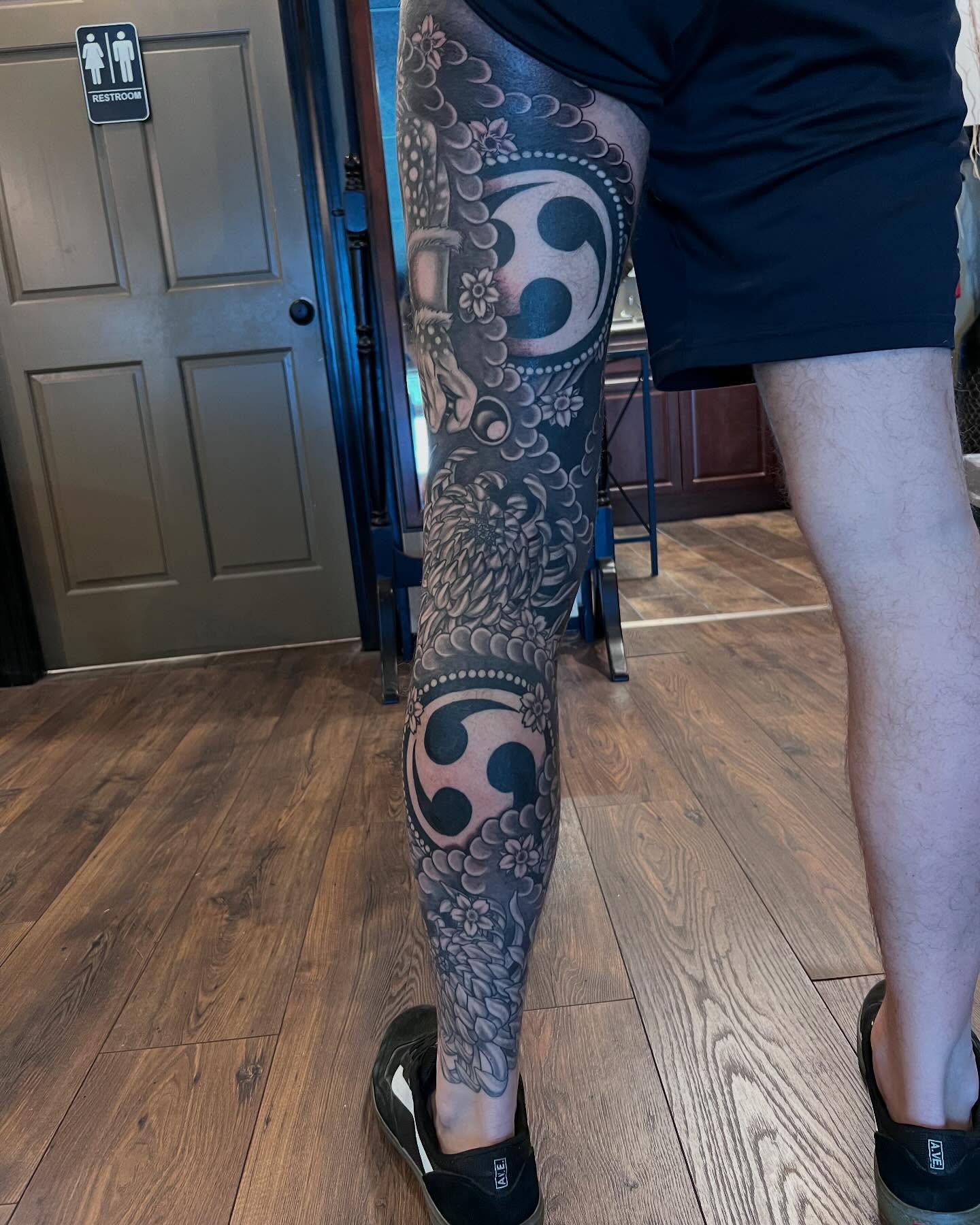 Floral and symbol dotwork tattoo on the calf by Jesse Gray