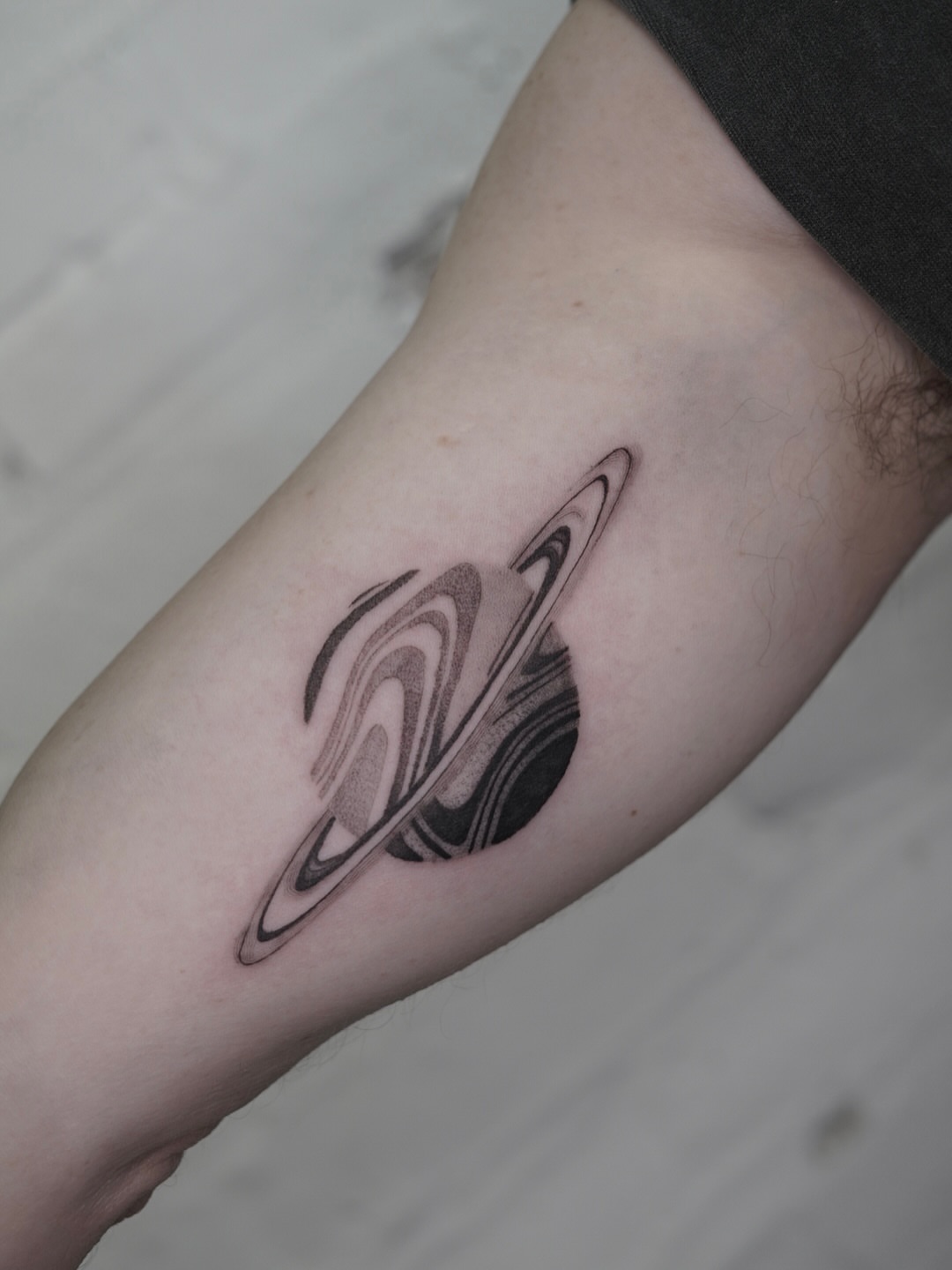 Saturn black and grey tattoo on the forearm by Josh Infante