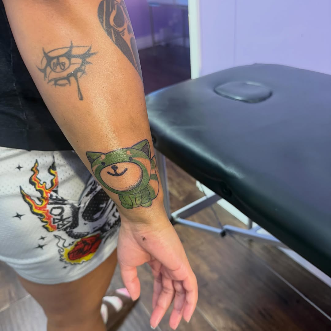 Cartoon red panda tattoo on the forearm by Jay