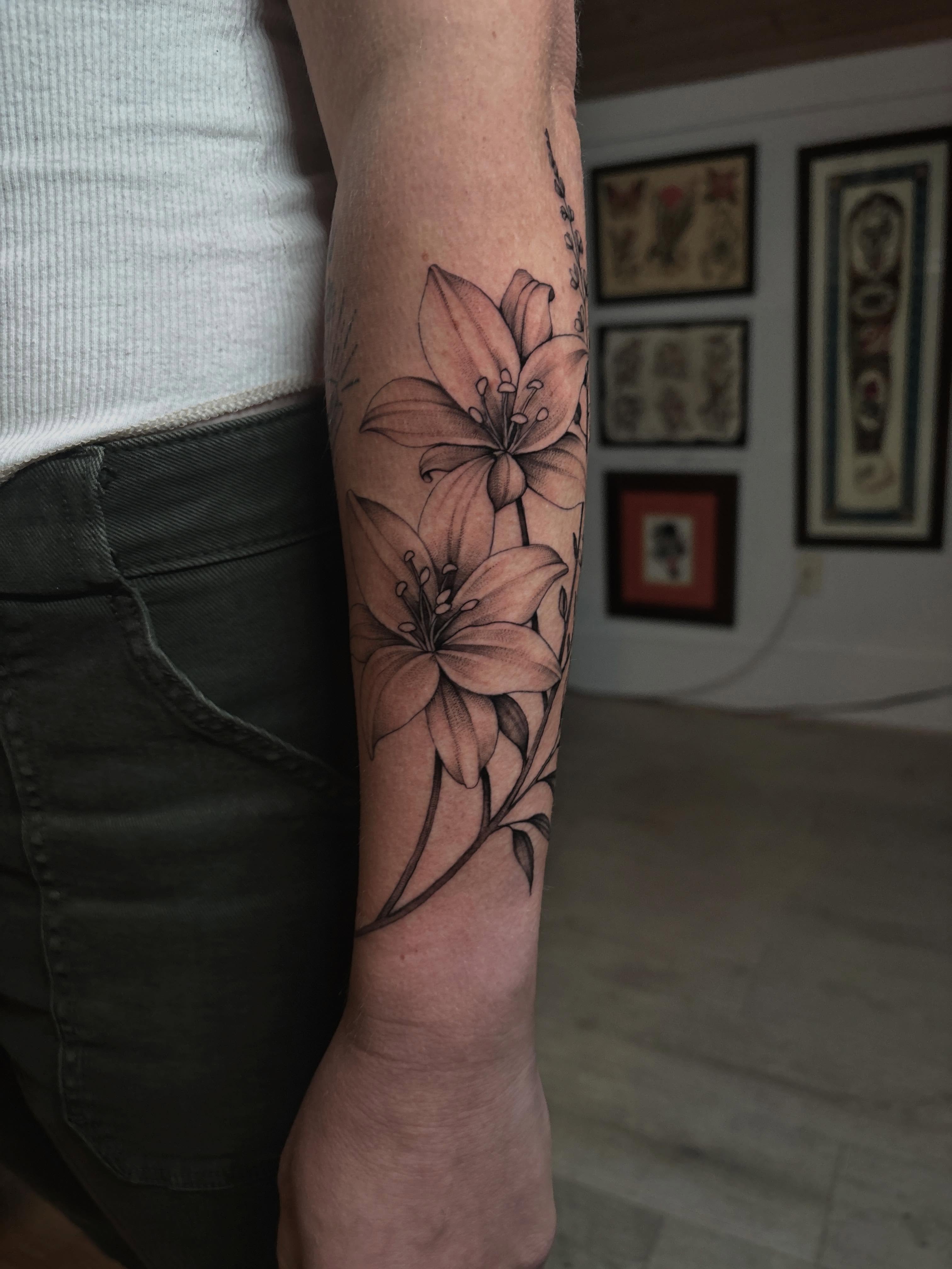 Lilies black and grey tattoo on the forearm by Emma Cotter