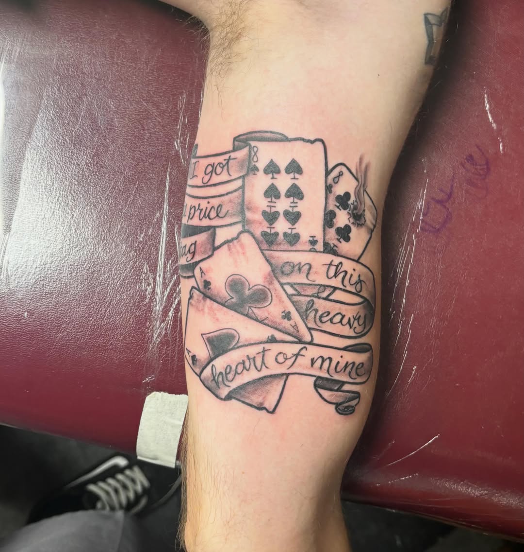 Playing cards and text black and grey tattoo on the forearm by Jeff Zuptich
