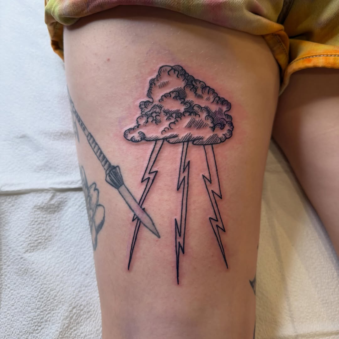Cloud with lightning bolts black and grey tattoo on the thigh by Eric Guntor, Philadelphia, Pennsylvania