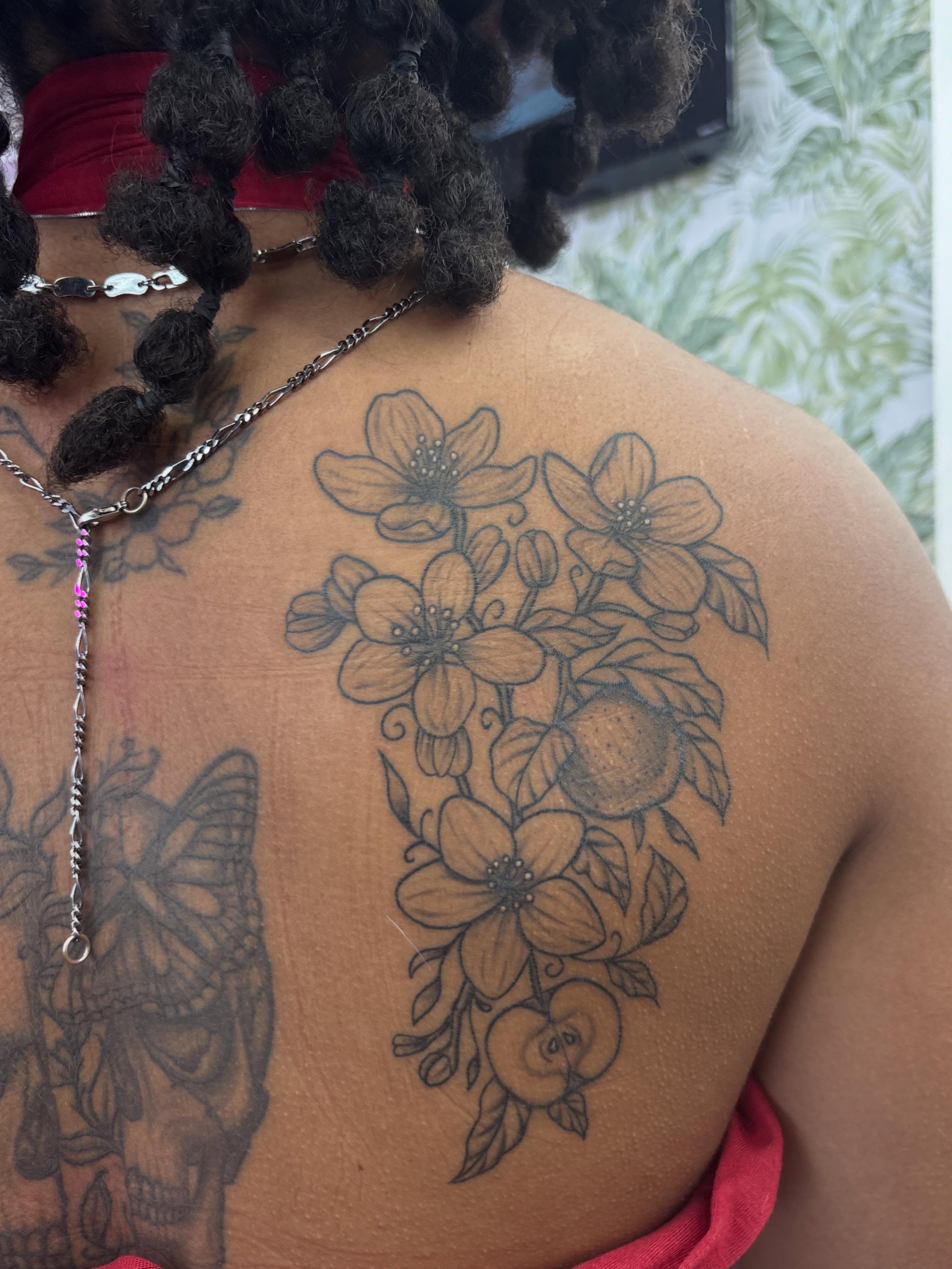 Flowers and fruit black and grey tattoo on the back by Skye California