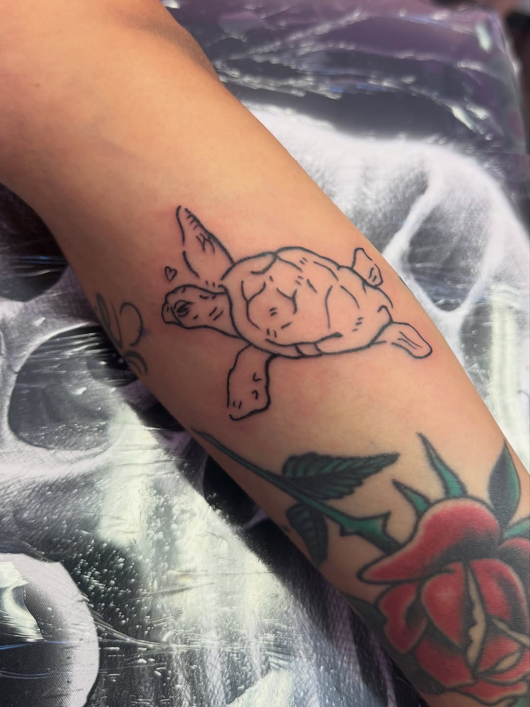 Sea turtle with hearts minimalist tattoo on the forearm by Lindsey