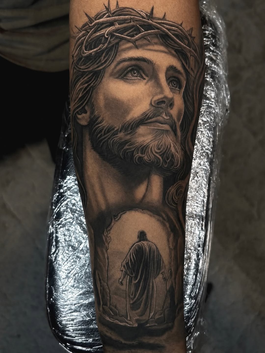 Jesus Christ portrait and figure realism tattoo on the forearm by Jayden A