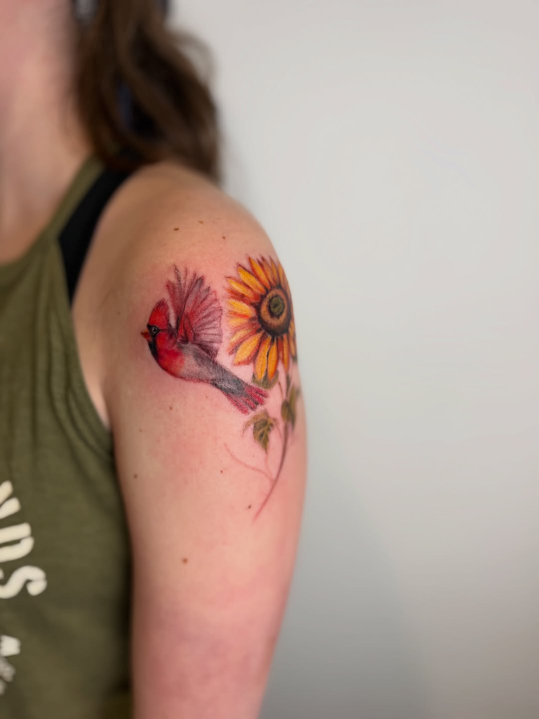 Cardinal and sunflower watercolor tattoo on the shoulder by Mackenzie