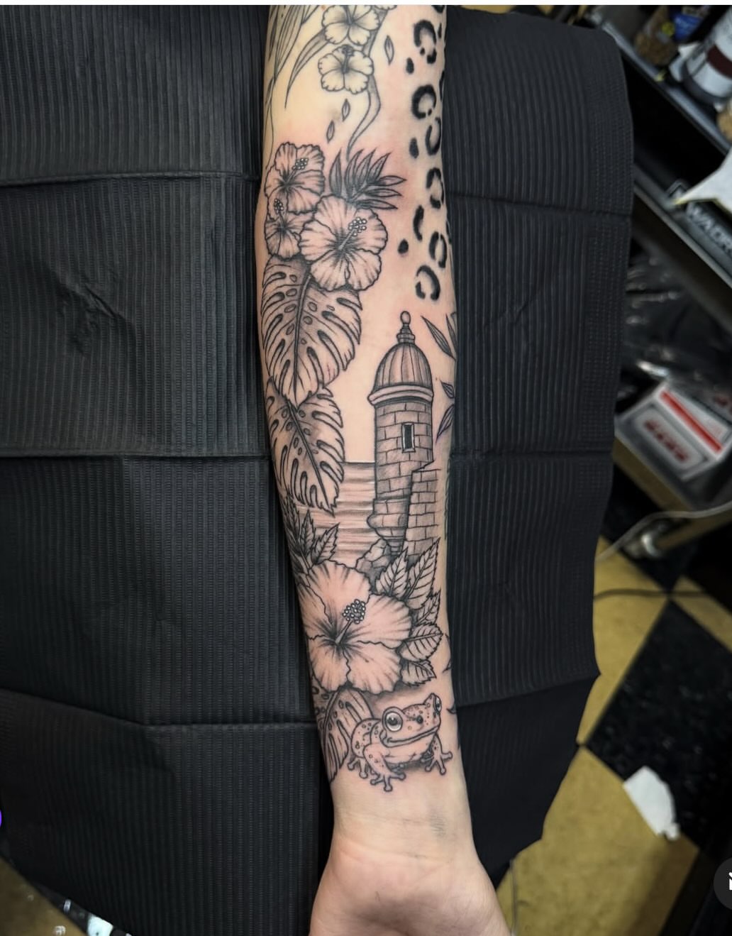 Lighthouse and tropical flowers black and grey tattoo on the forearm by Gary Chase