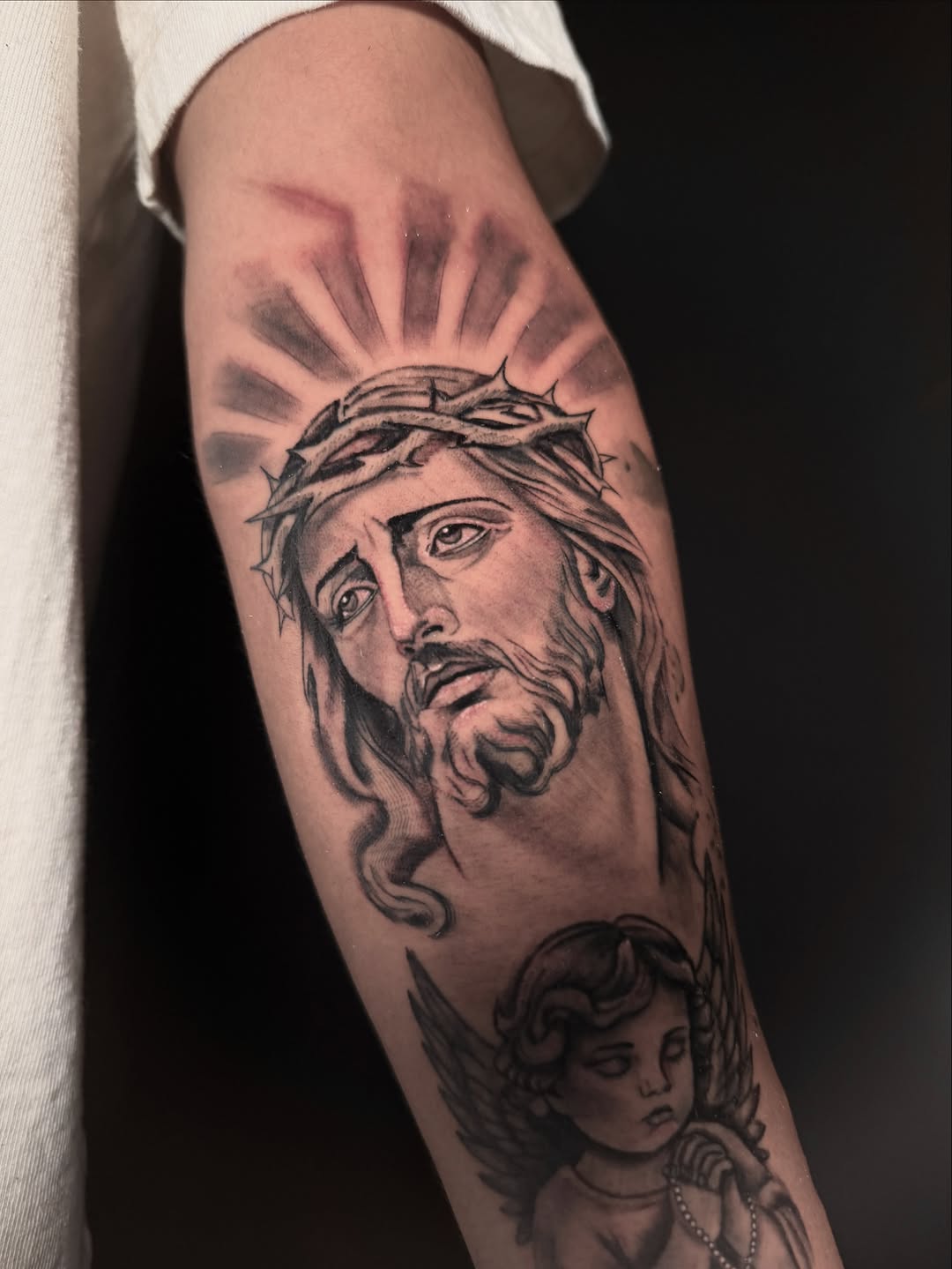 Jesus Christ and cherub realism tattoo on the forearm by Alex Cantor
