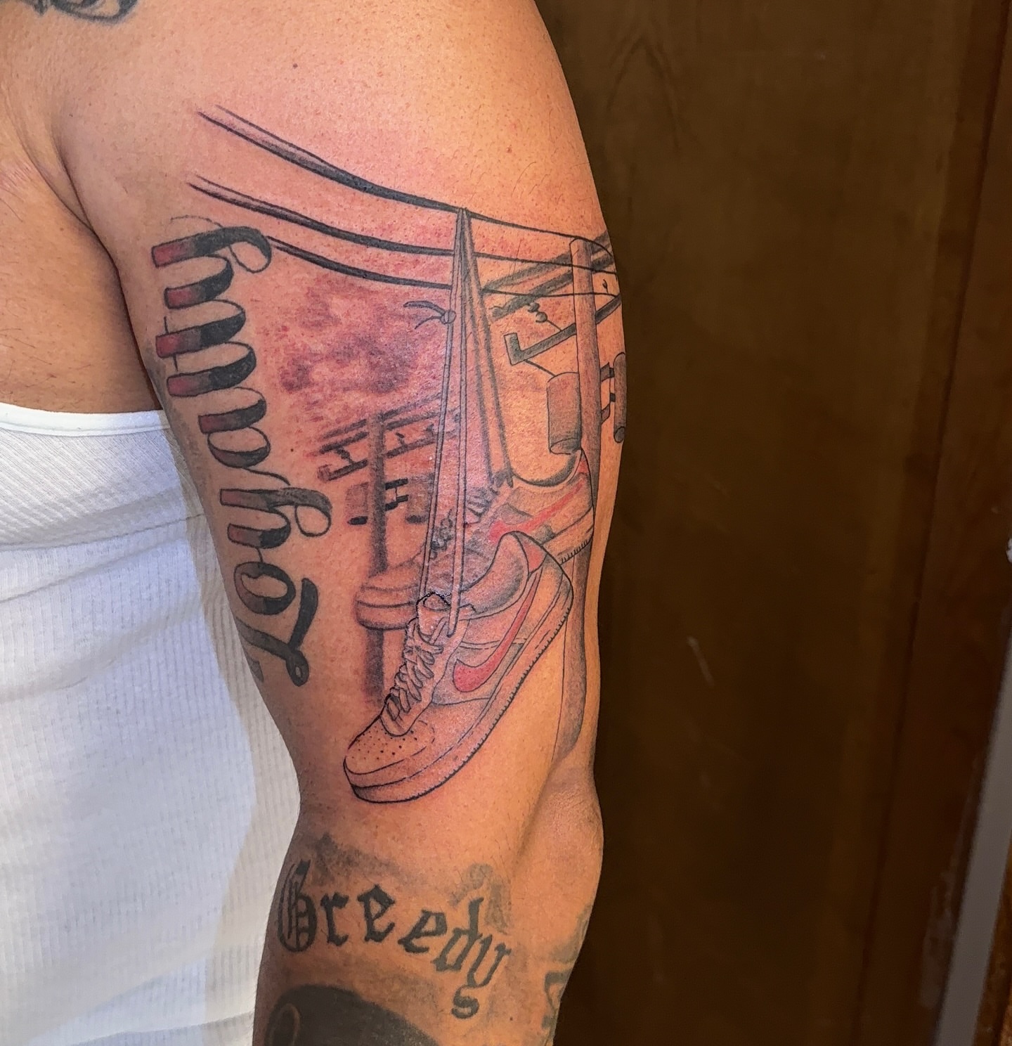 Sneakers and lettering black and grey tattoo on the upper arm by XoticTherapy, Las Vegas, Nevada