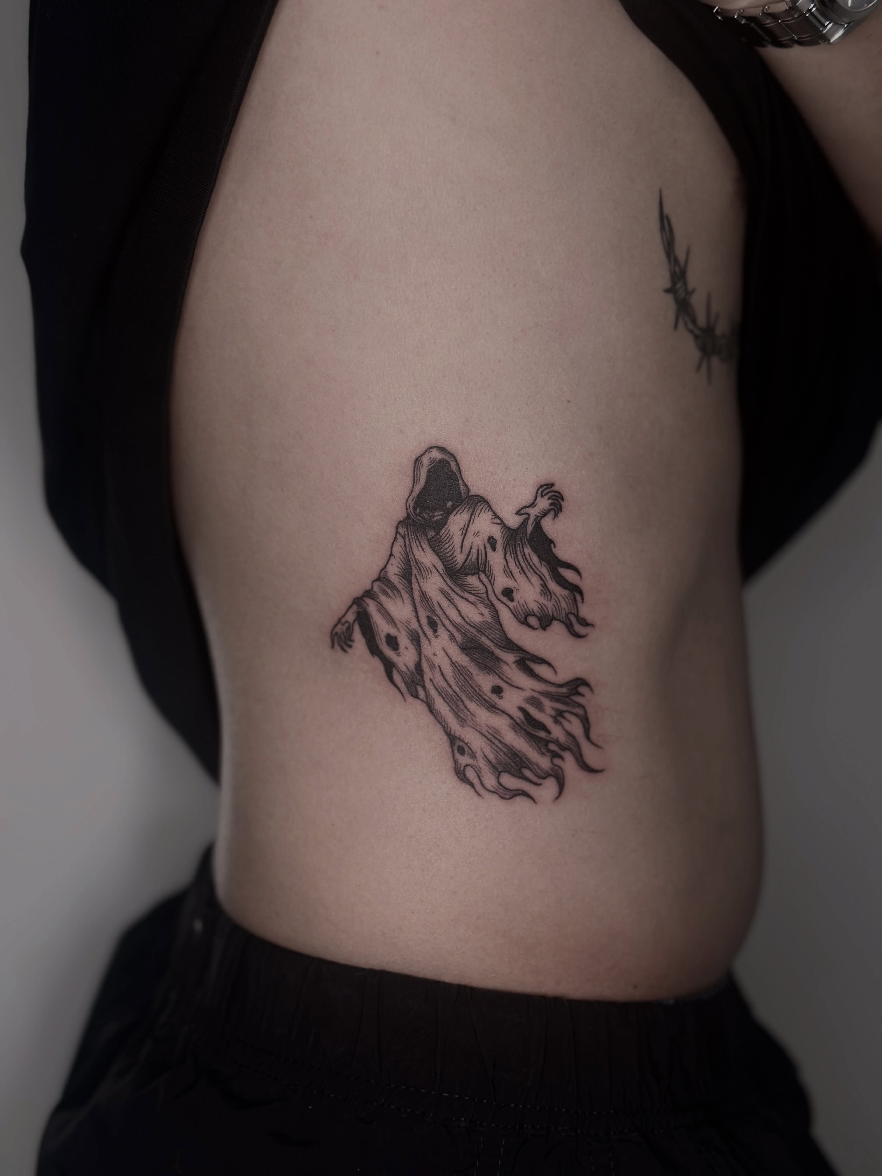 Ghostly figure black and grey tattoo on the ribs by Zecember