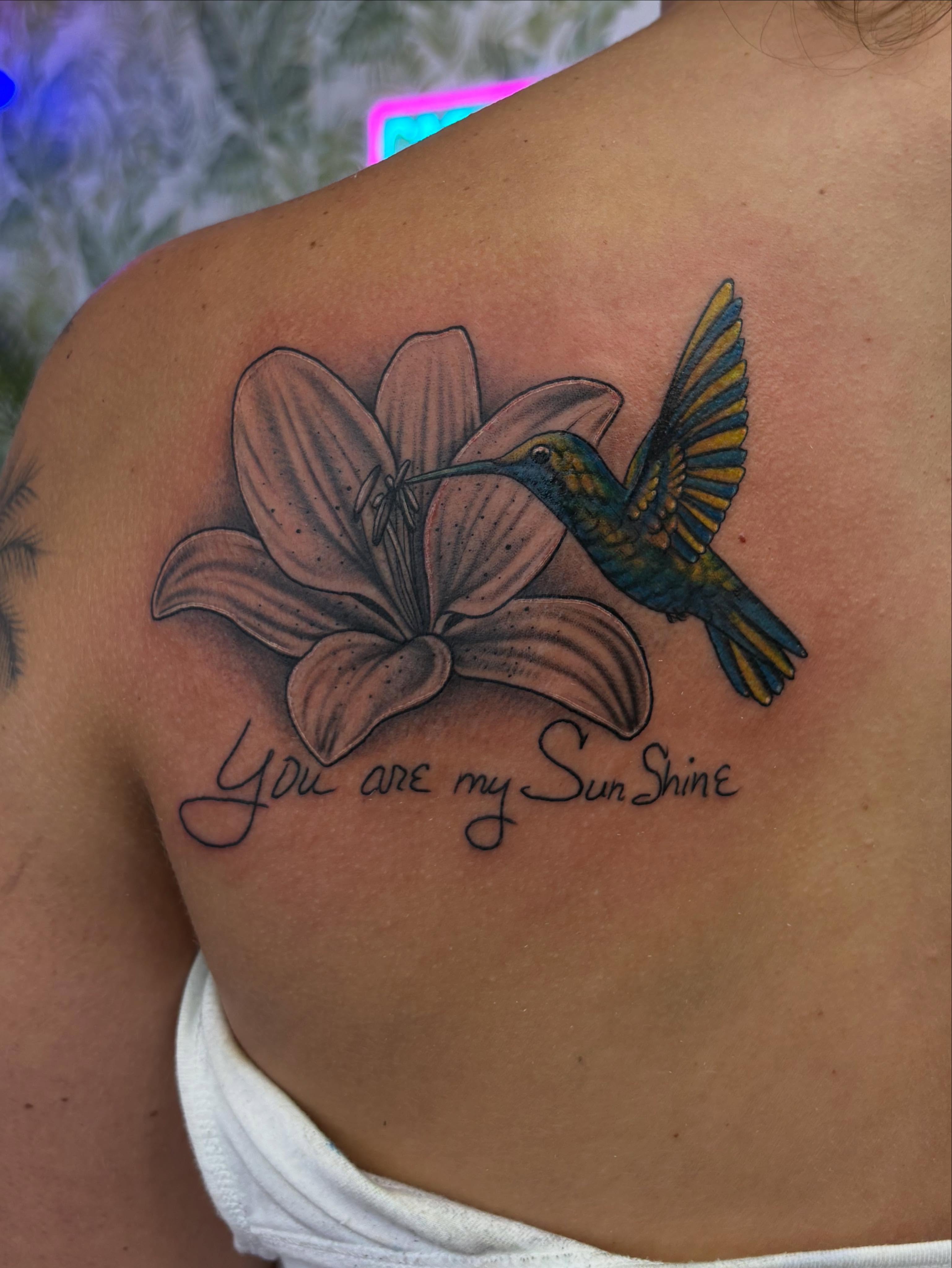 Hummingbird and lily realism tattoo on the shoulder by Skye California