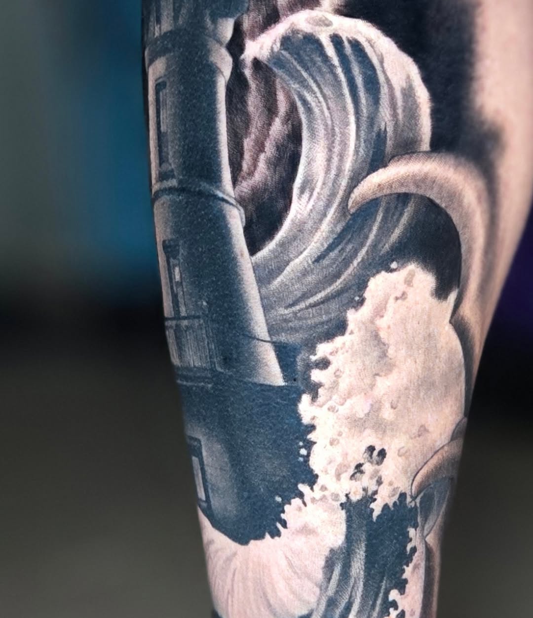 Wave and building realism tattoo on the forearm by Jeff Stager