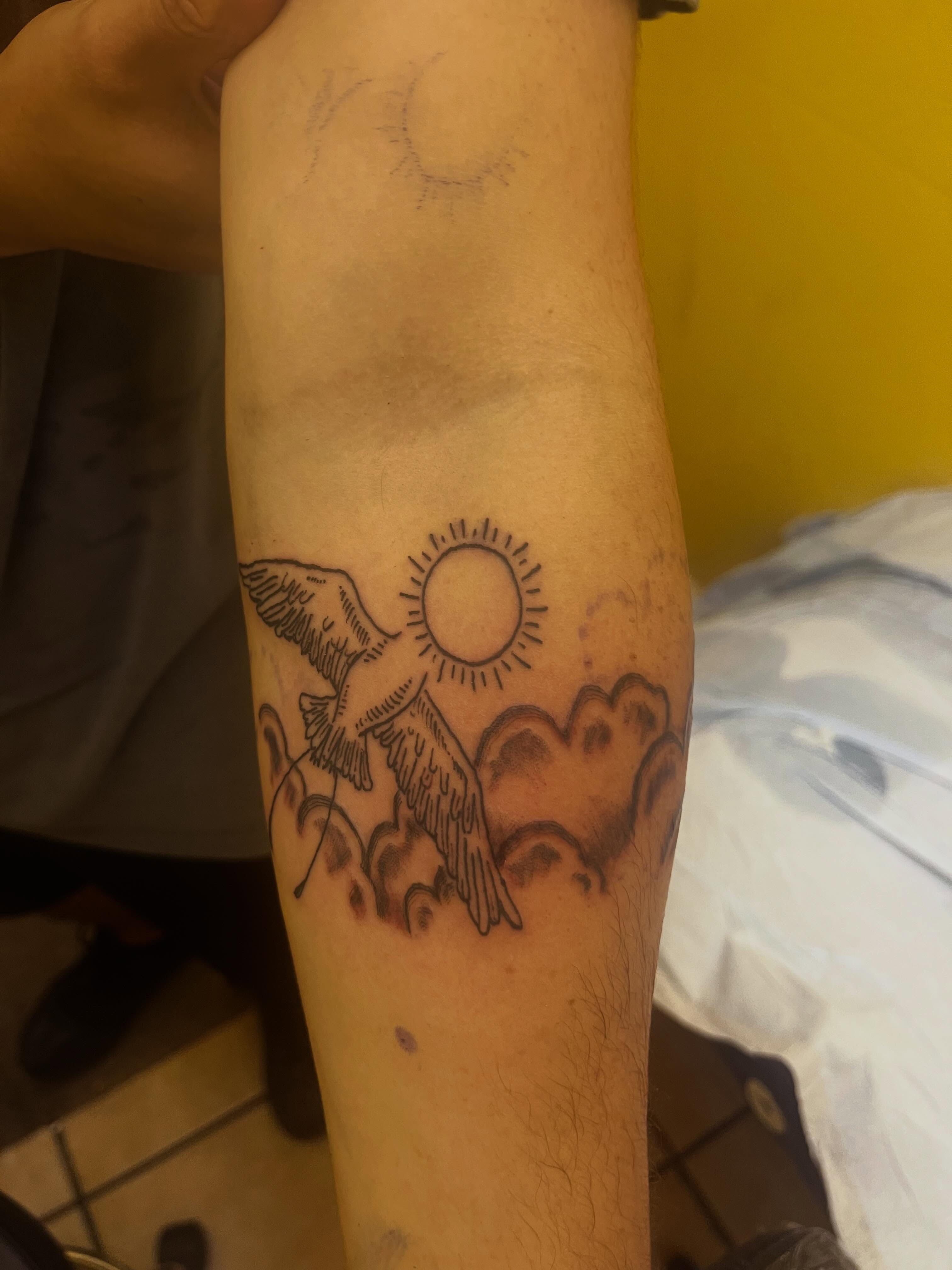 Bird flying towards sun black and grey tattoo on the forearm by Rafaela Lopez
