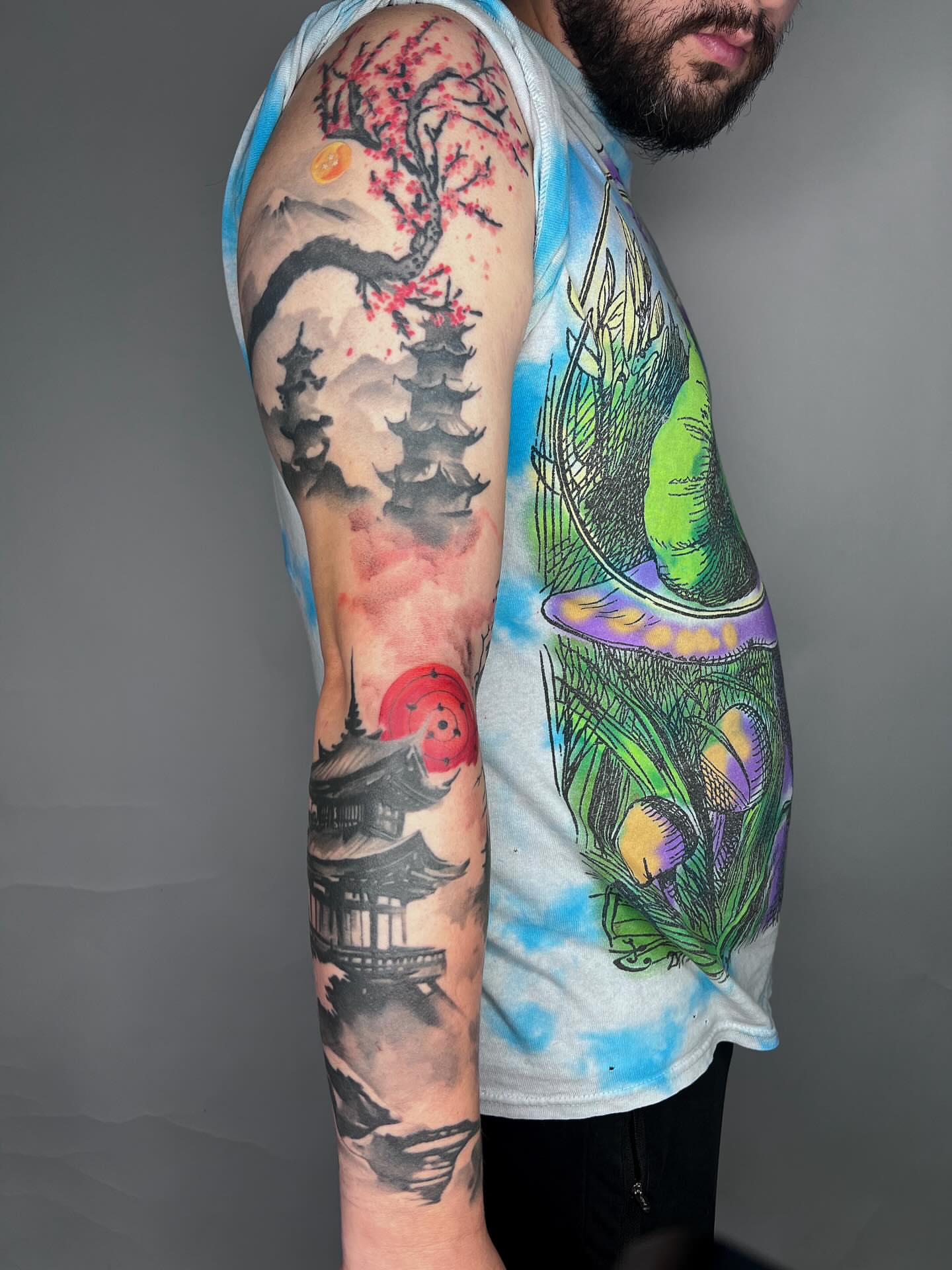 Cherry blossoms and pagoda japanese irezumi tattoo on the upper arm by Dolph.