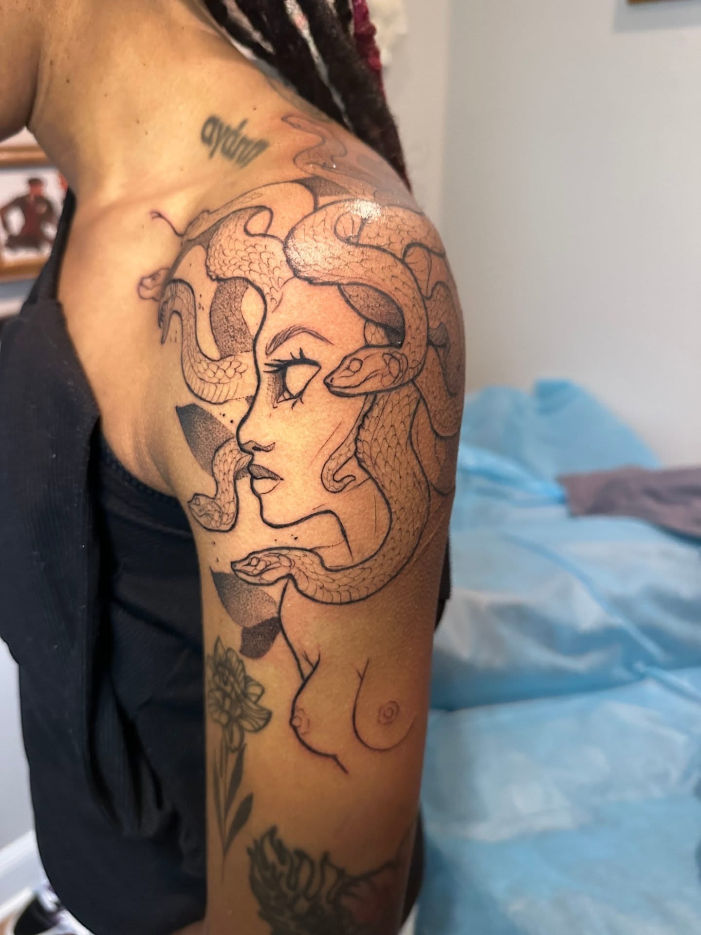 Woman with snakes dotwork tattoo on the upper arm by Sasha Wren