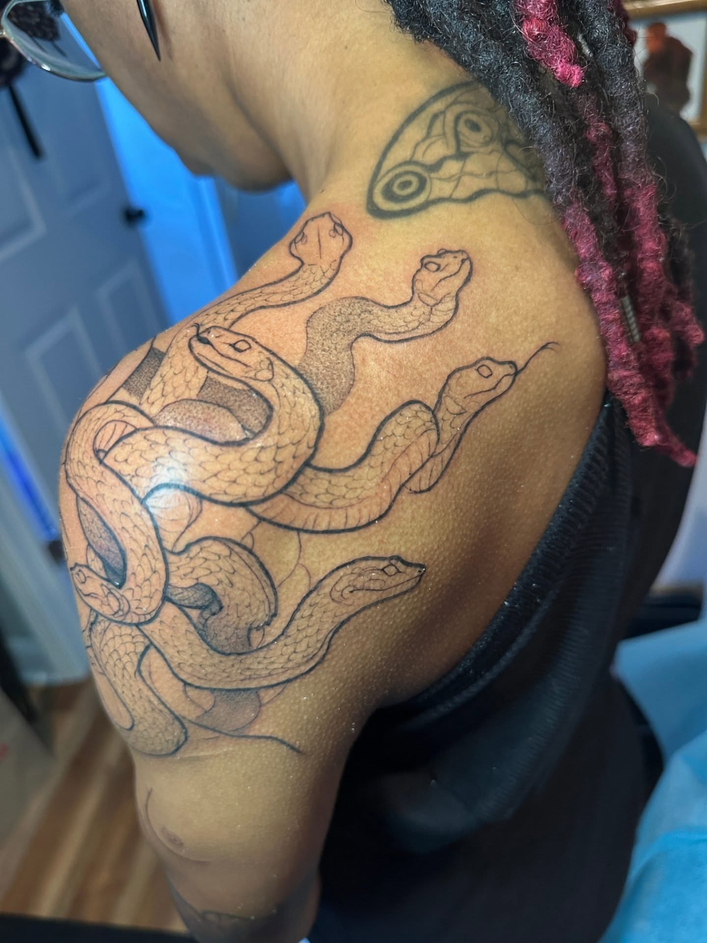 Snakes black and grey tattoo on the shoulder by Sasha Wren