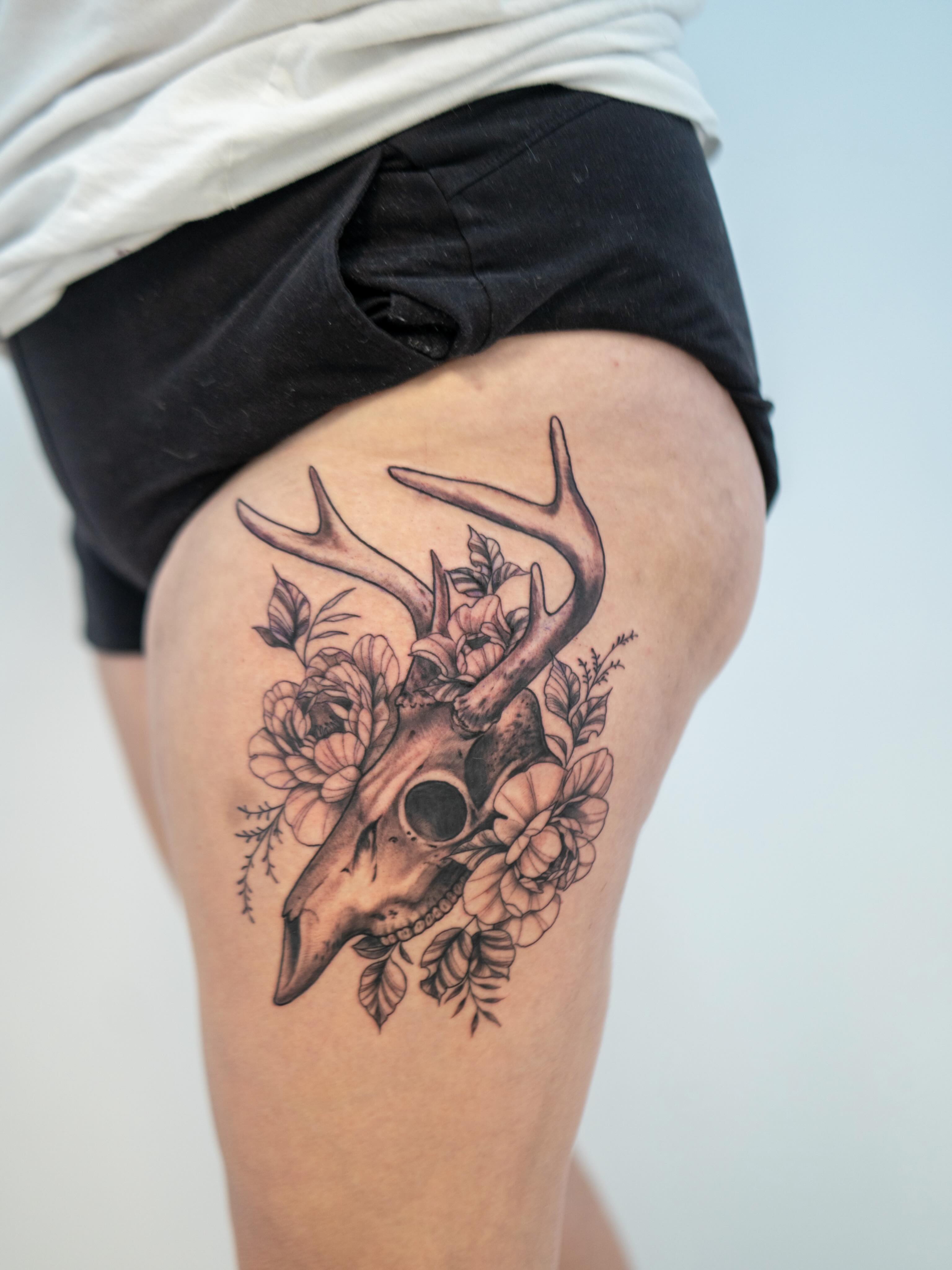 Deer skull with flowers realism tattoo on the thigh by Skylar