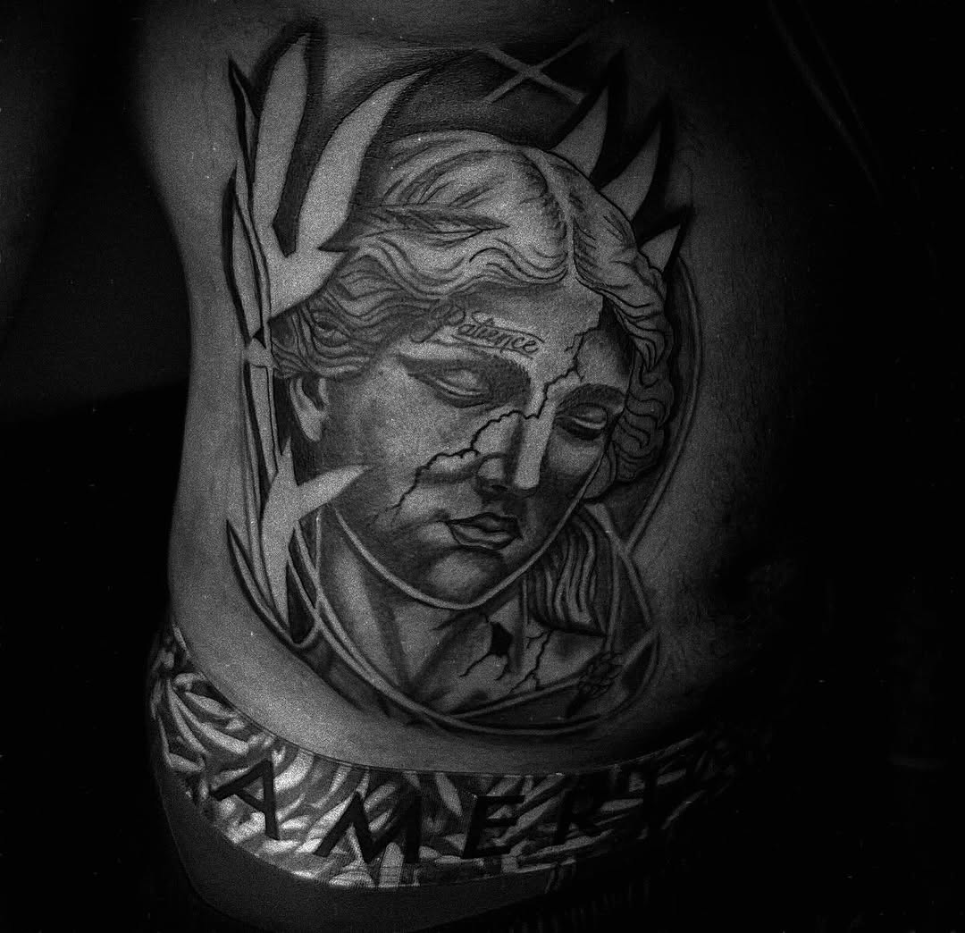 Cracked statue head with 'patience' text tattoo on the torso by @tattsbyleek