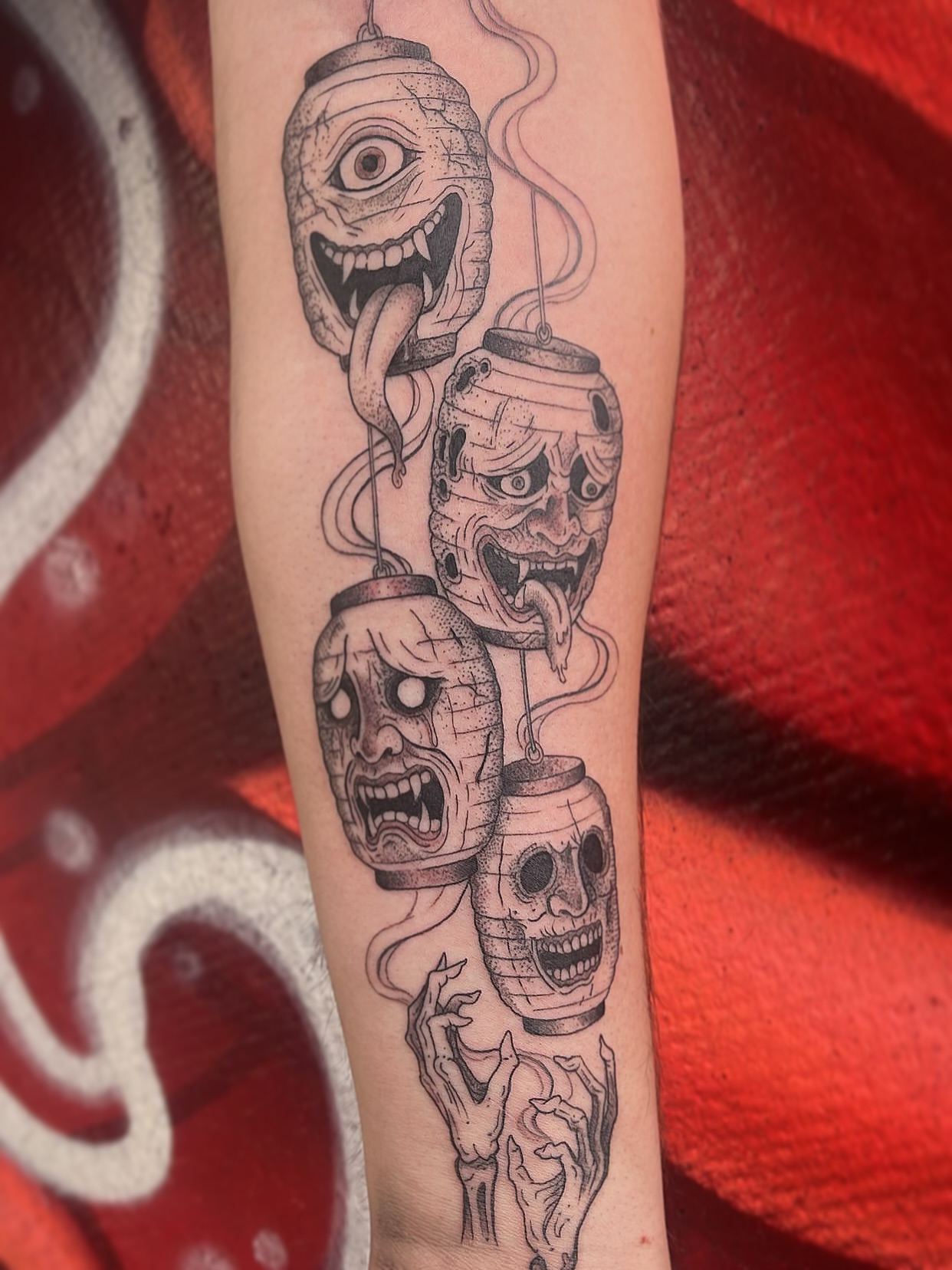 Skulls and faces black and grey tattoo on the forearm by Elle Miller
