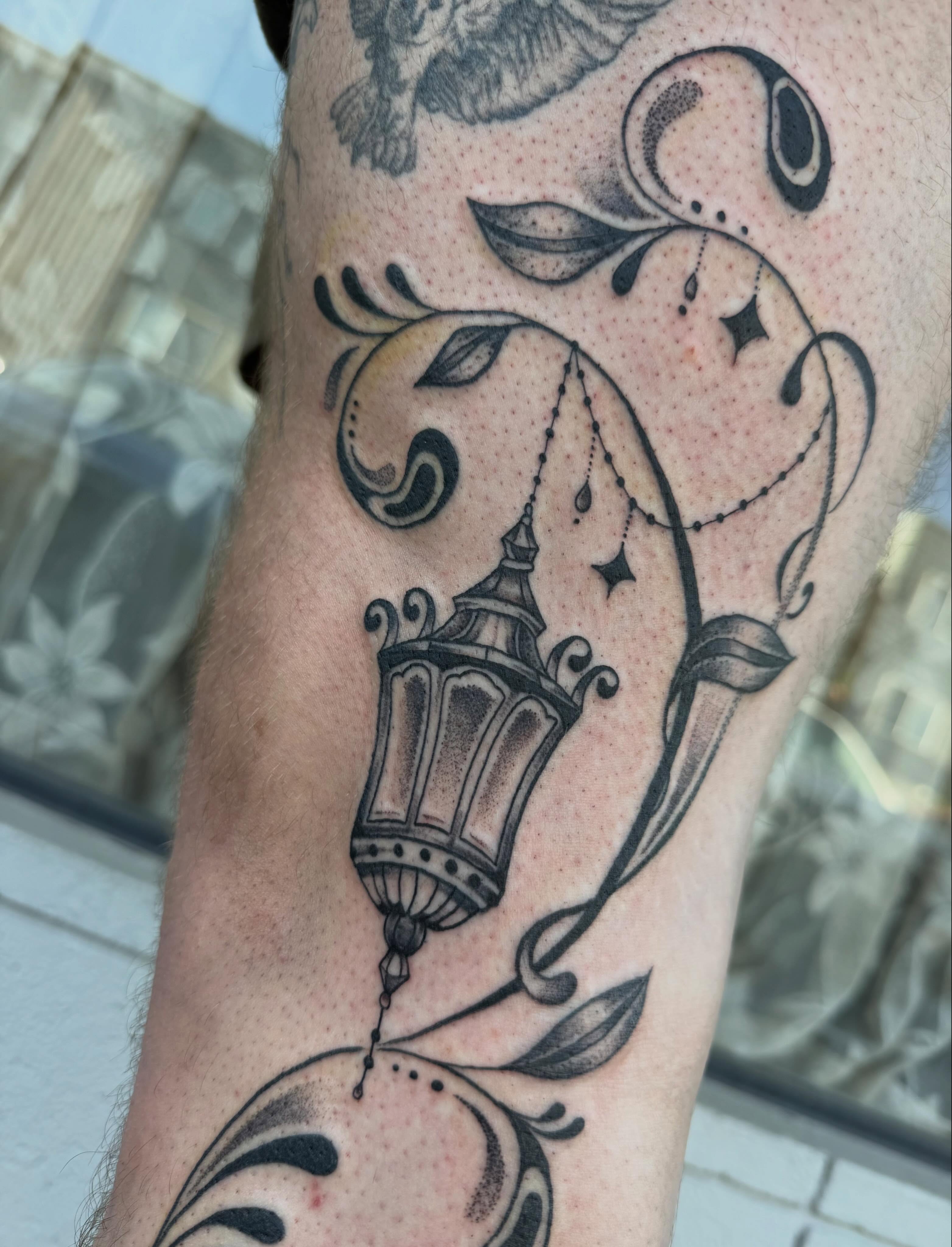 Lantern and floral black and grey tattoo on the forearm by Ellie MacPherson🌱🧚🏻‍♀️🫧