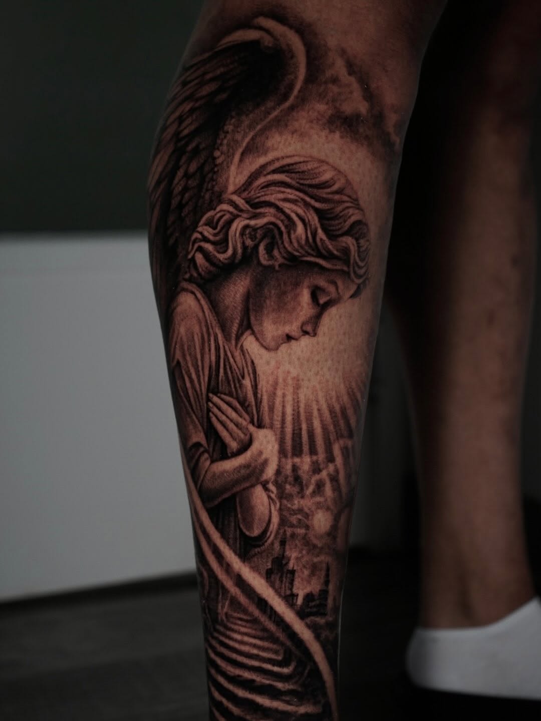 Angel with praying hands and cityscape realism tattoo on the forearm by Sabrina Lakhaysy, Fort Worth, Texas