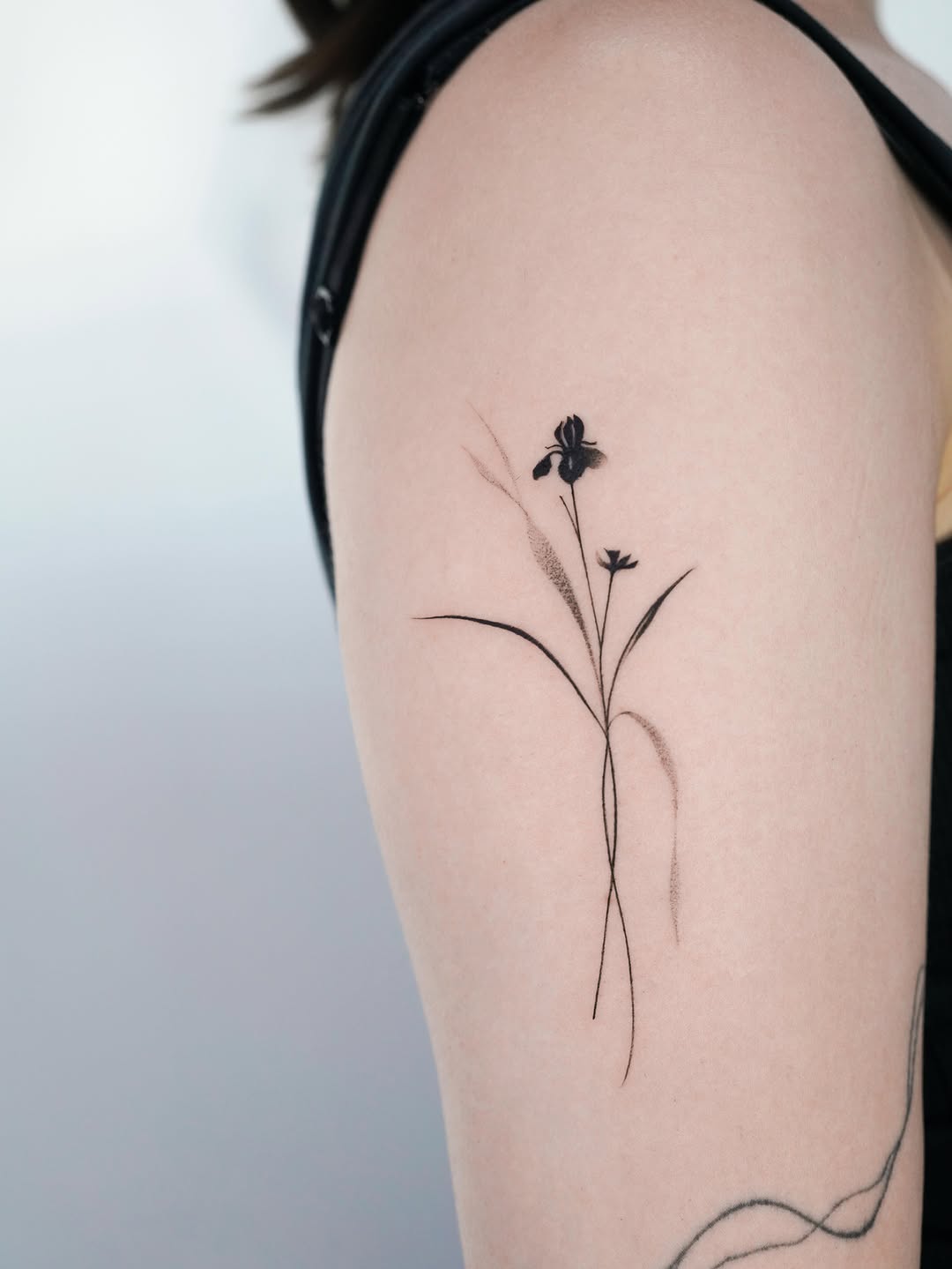 Iris flower blackwork tattoo on the upper arm by 초현실과 현실 그 사이를 그리다.