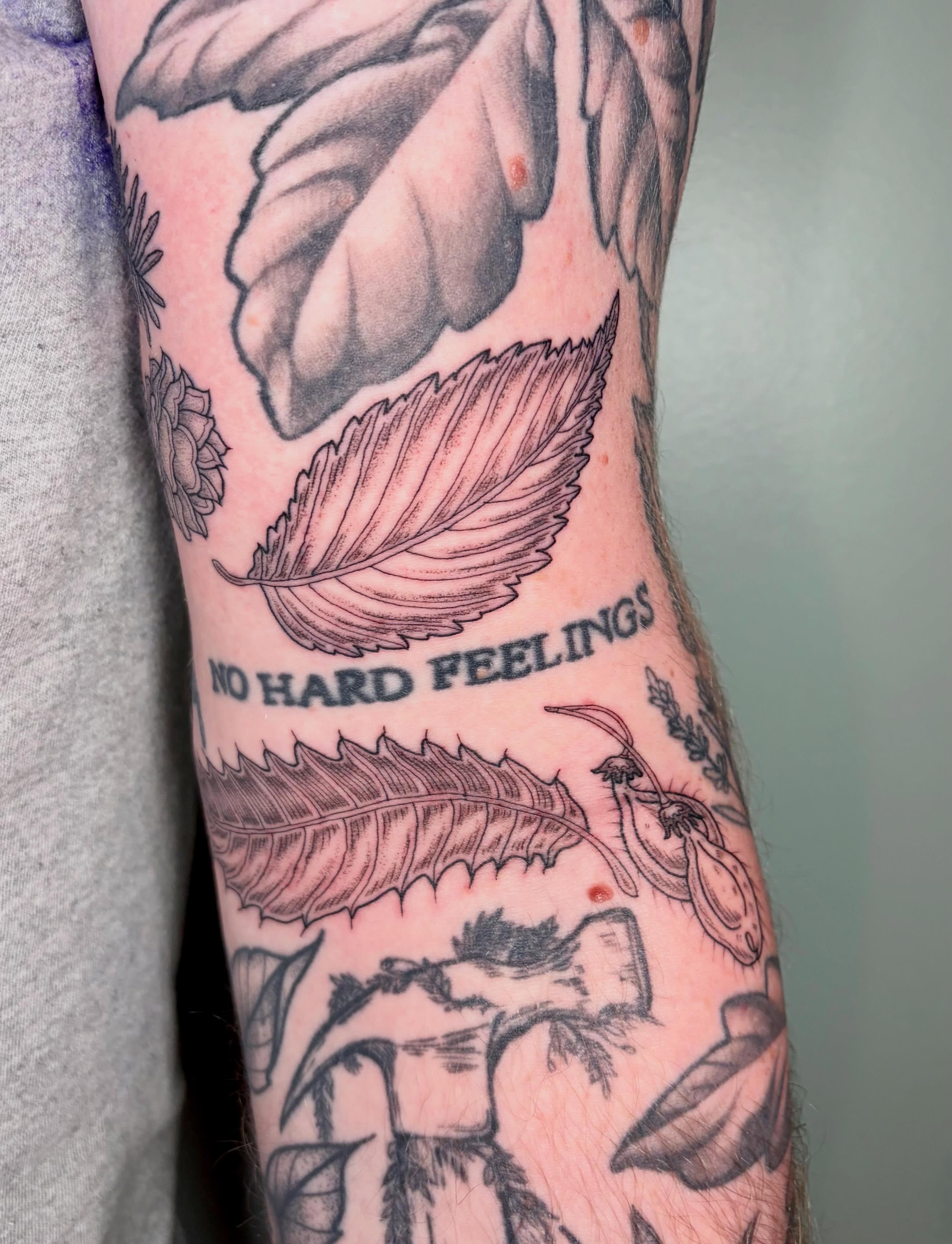 Leaves and text black and grey tattoo on the forearm by Sarah Roach