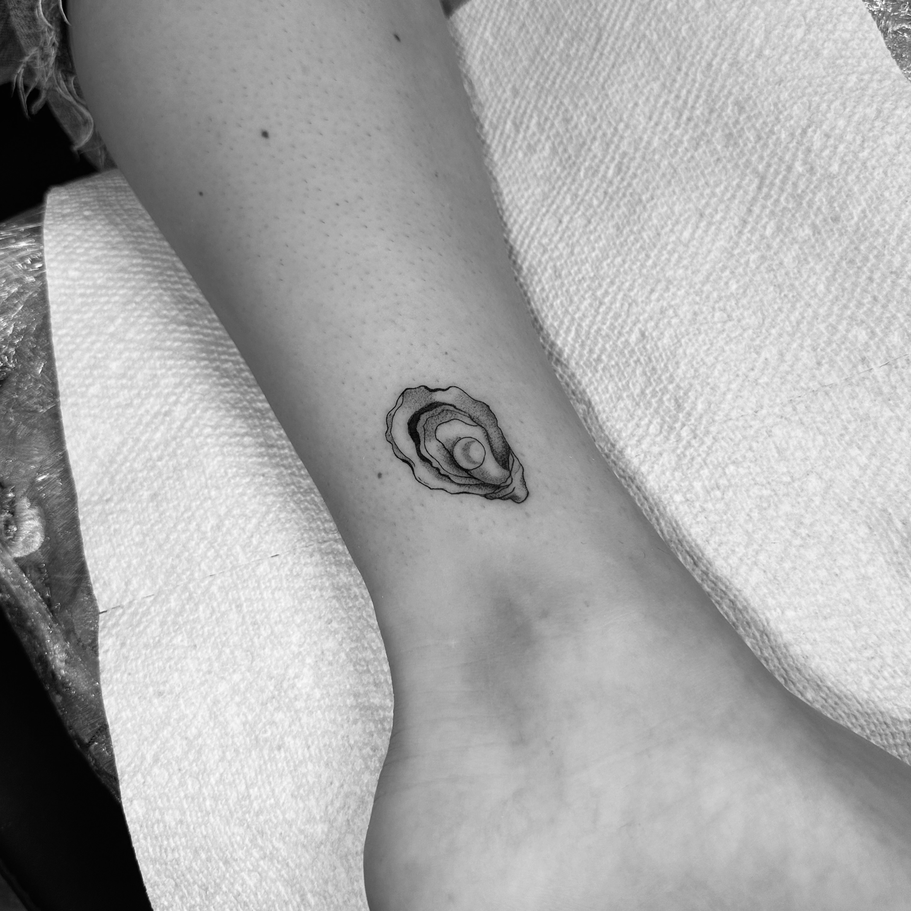 Oyster shell black and grey tattoo on the forearm by Leo Fernandes, Danvers, Massachusetts