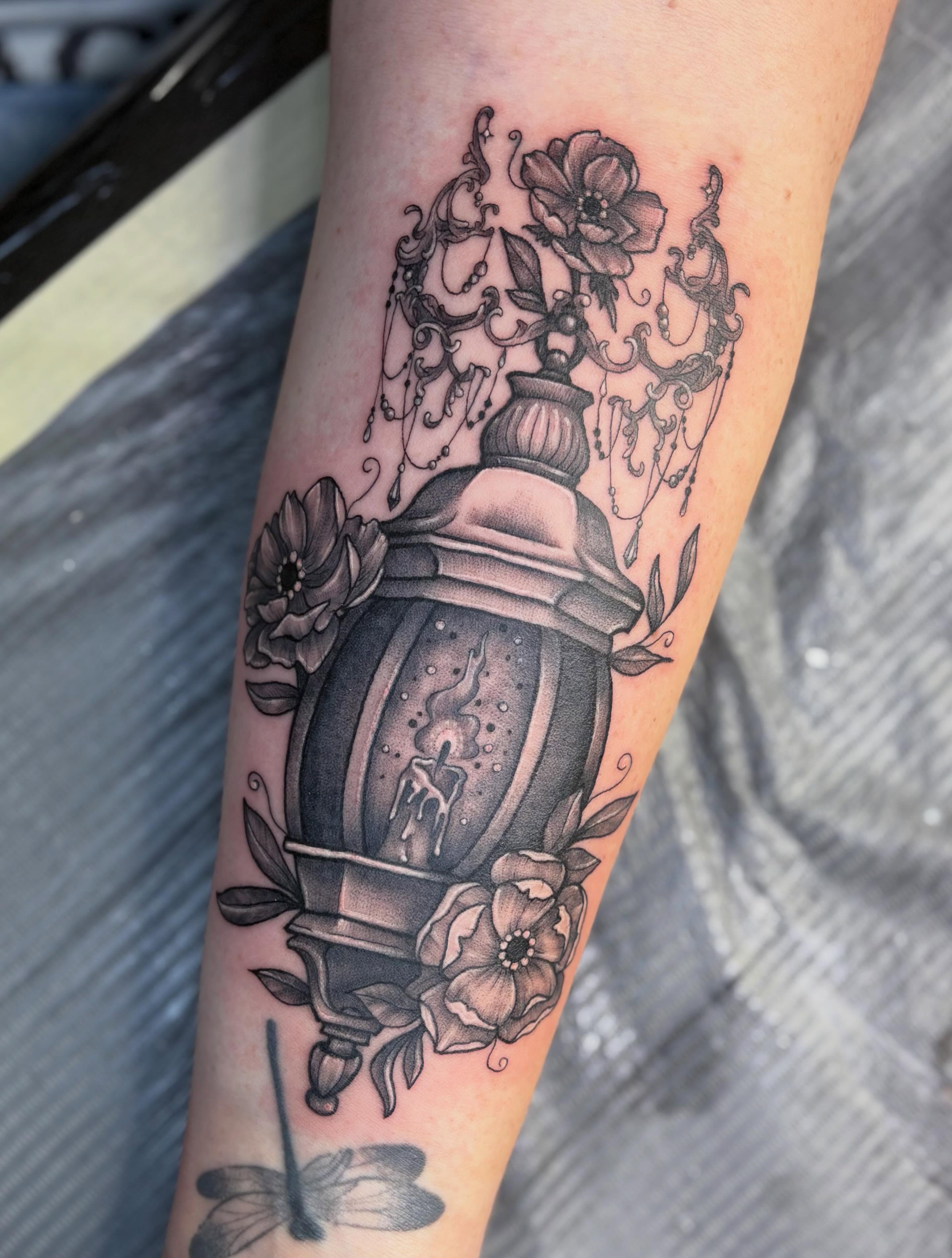 Lantern and flowers black and grey tattoo on the forearm by Olivia Buch
