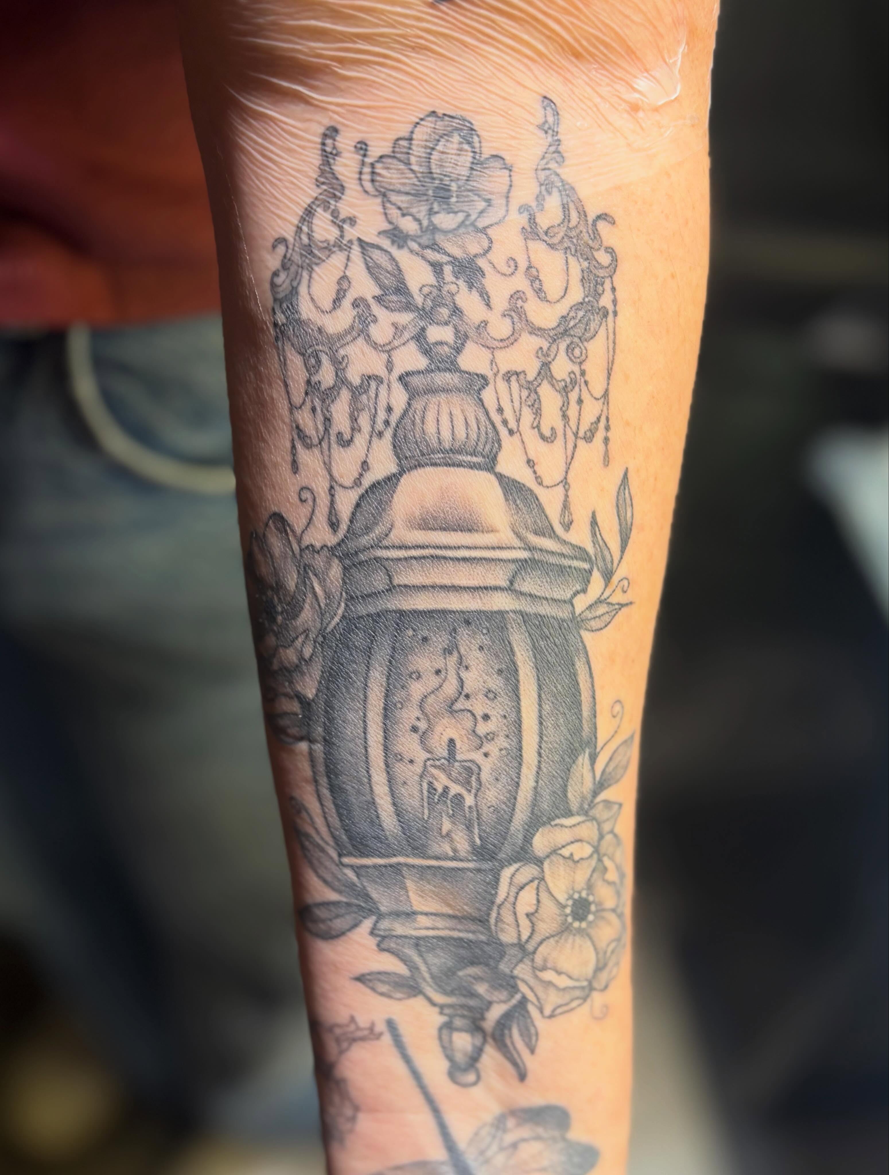 Lantern with candle black and grey tattoo on the forearm by Olivia Buch