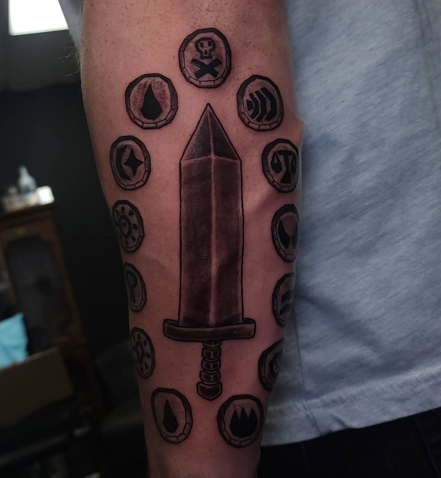 Sword and symbols black and grey tattoo on the forearm by xavia
