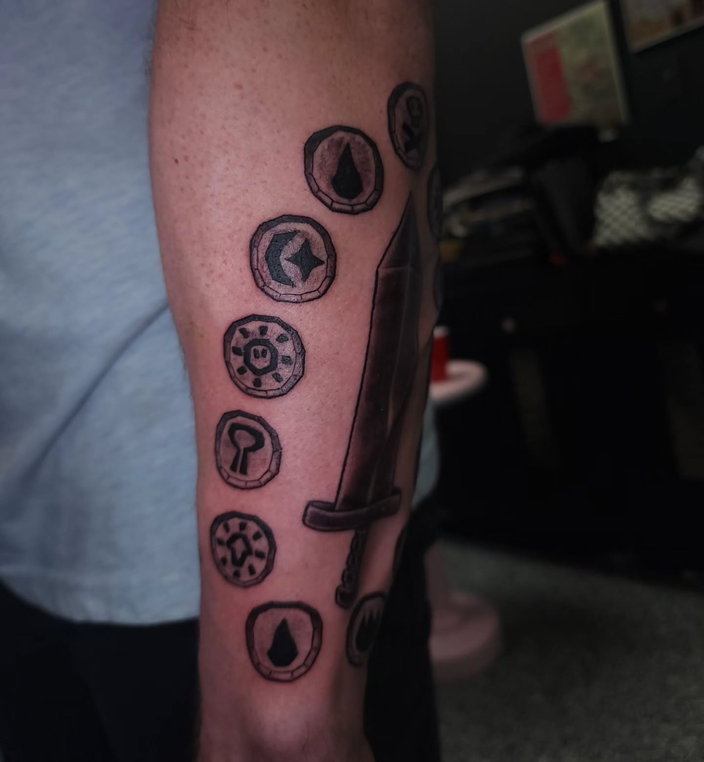 Sword and coins black and grey tattoo on the forearm by xavia
