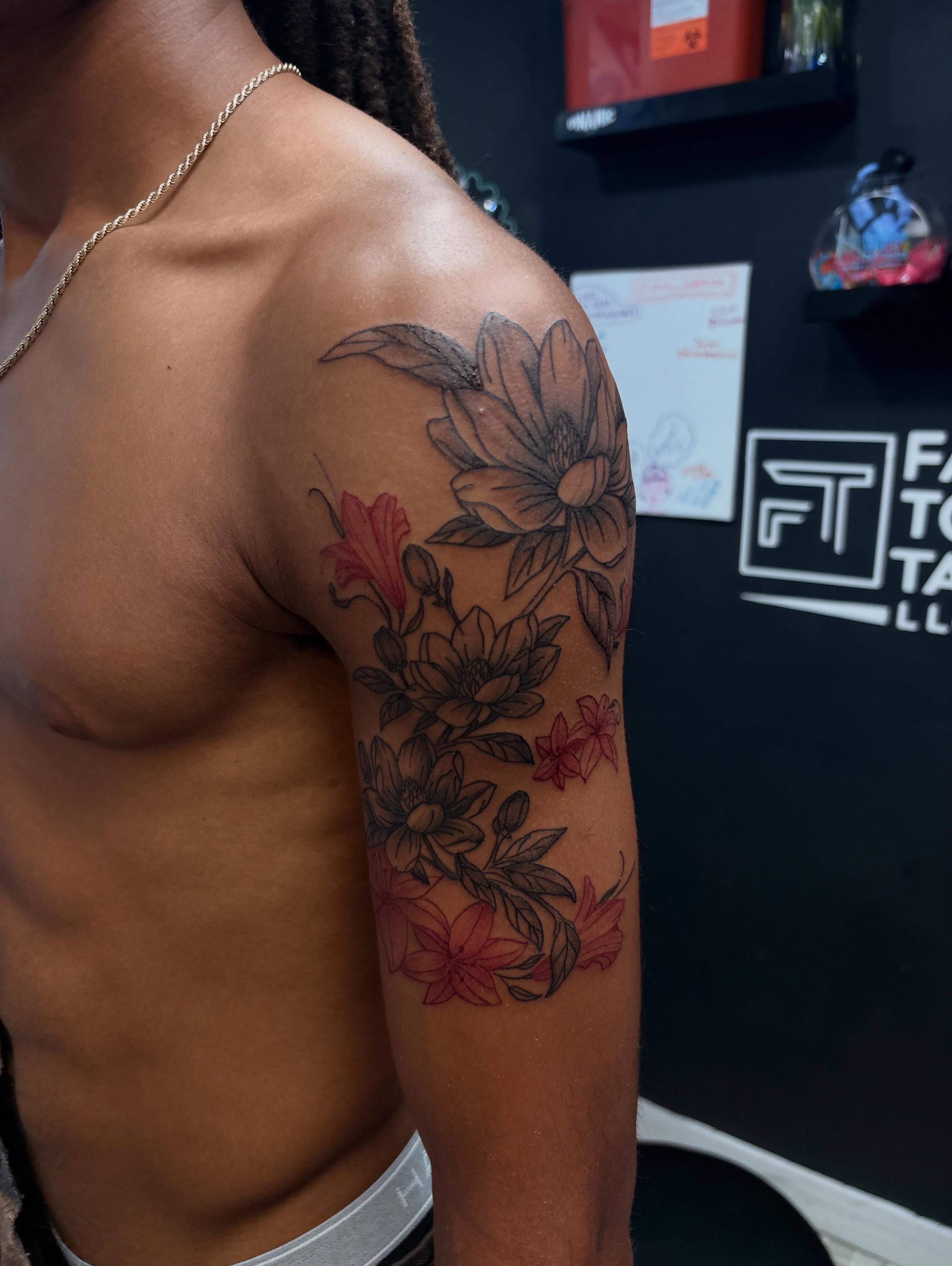 Floral arrangement black and grey tattoo on the upper arm by 𝓚𝓪𝓻𝓶𝓪💫