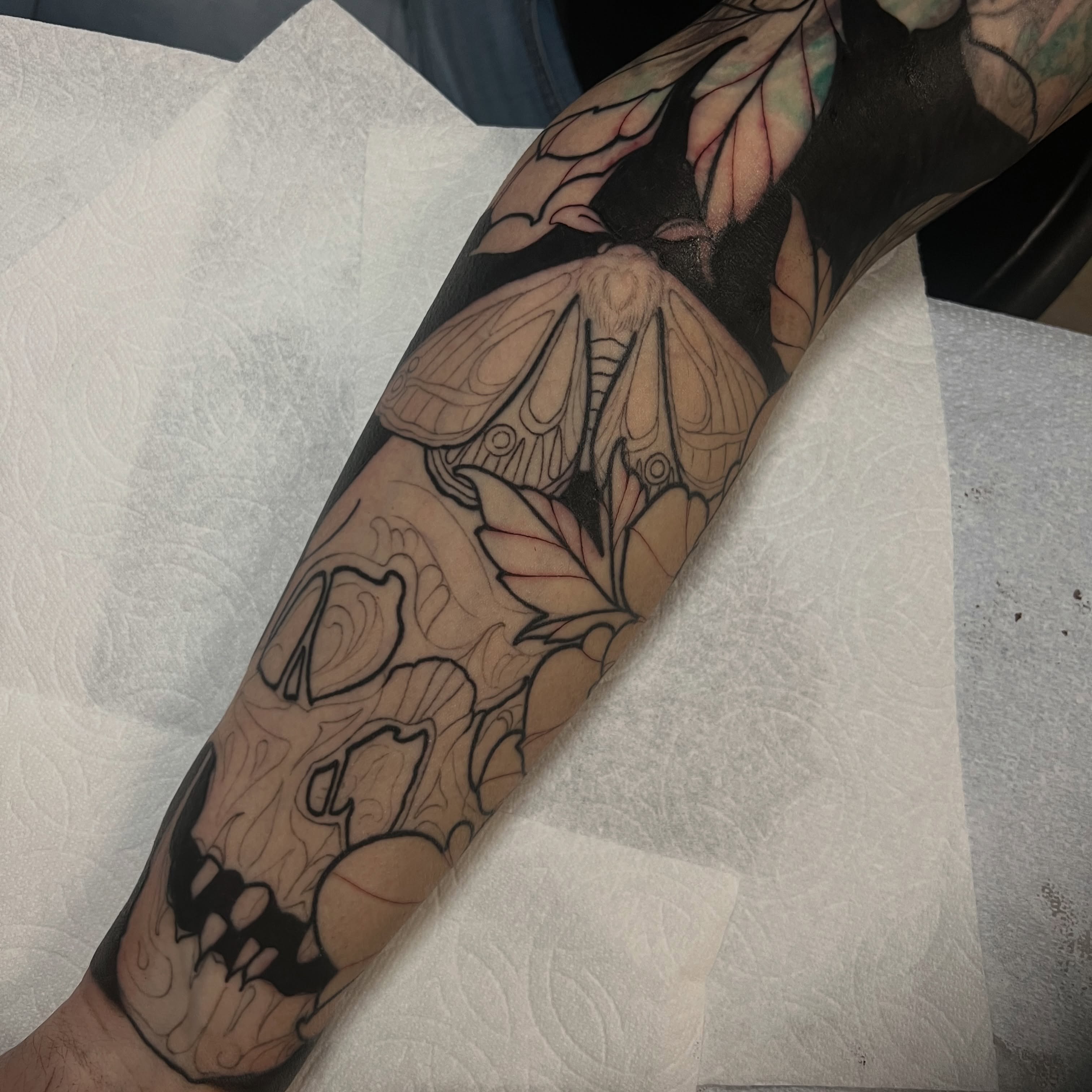 Moth and leaves black and grey tattoo on the forearm by Rennie Tattoo