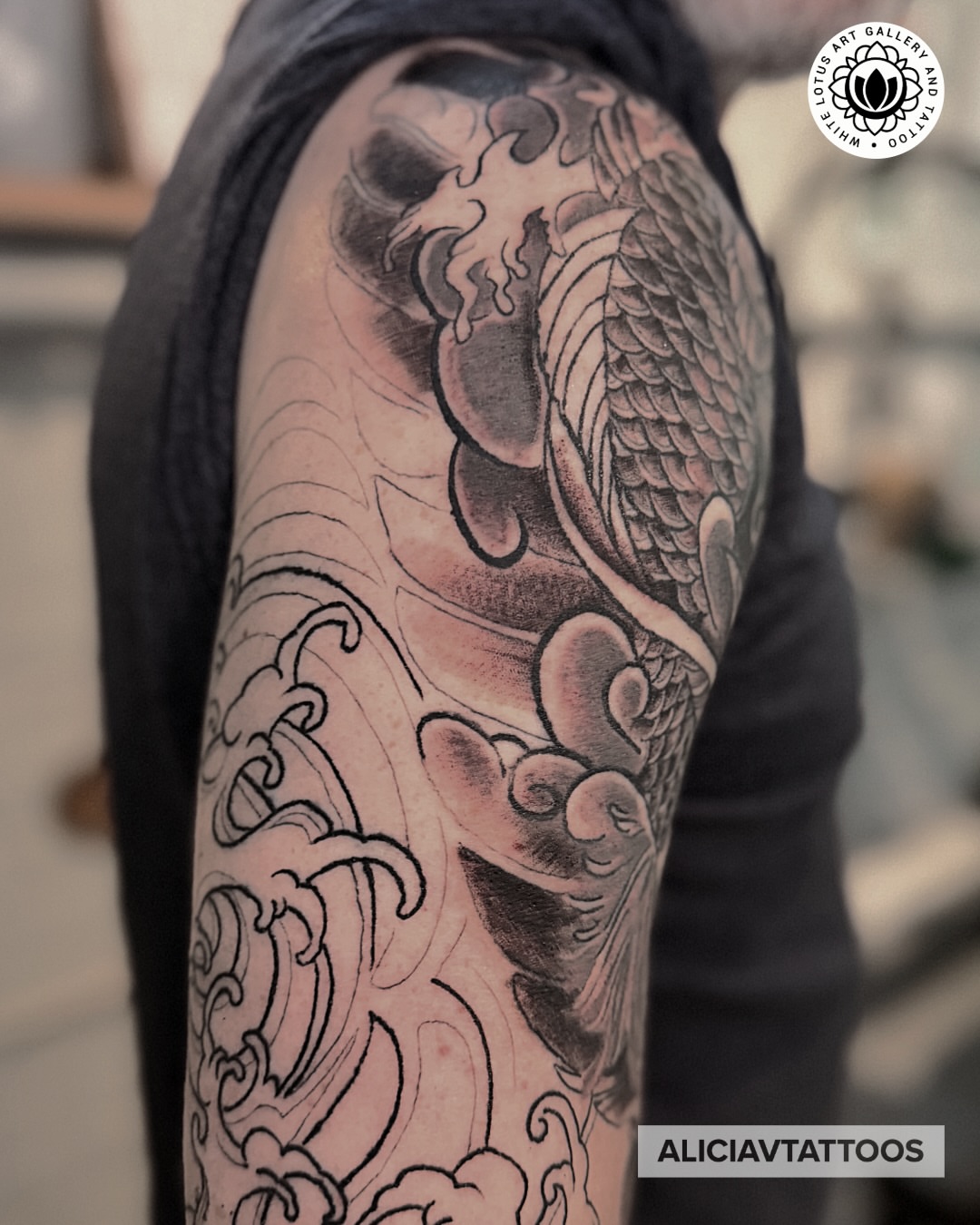 Koi fish black and grey tattoo on the upper arm by Alicia Vasquez