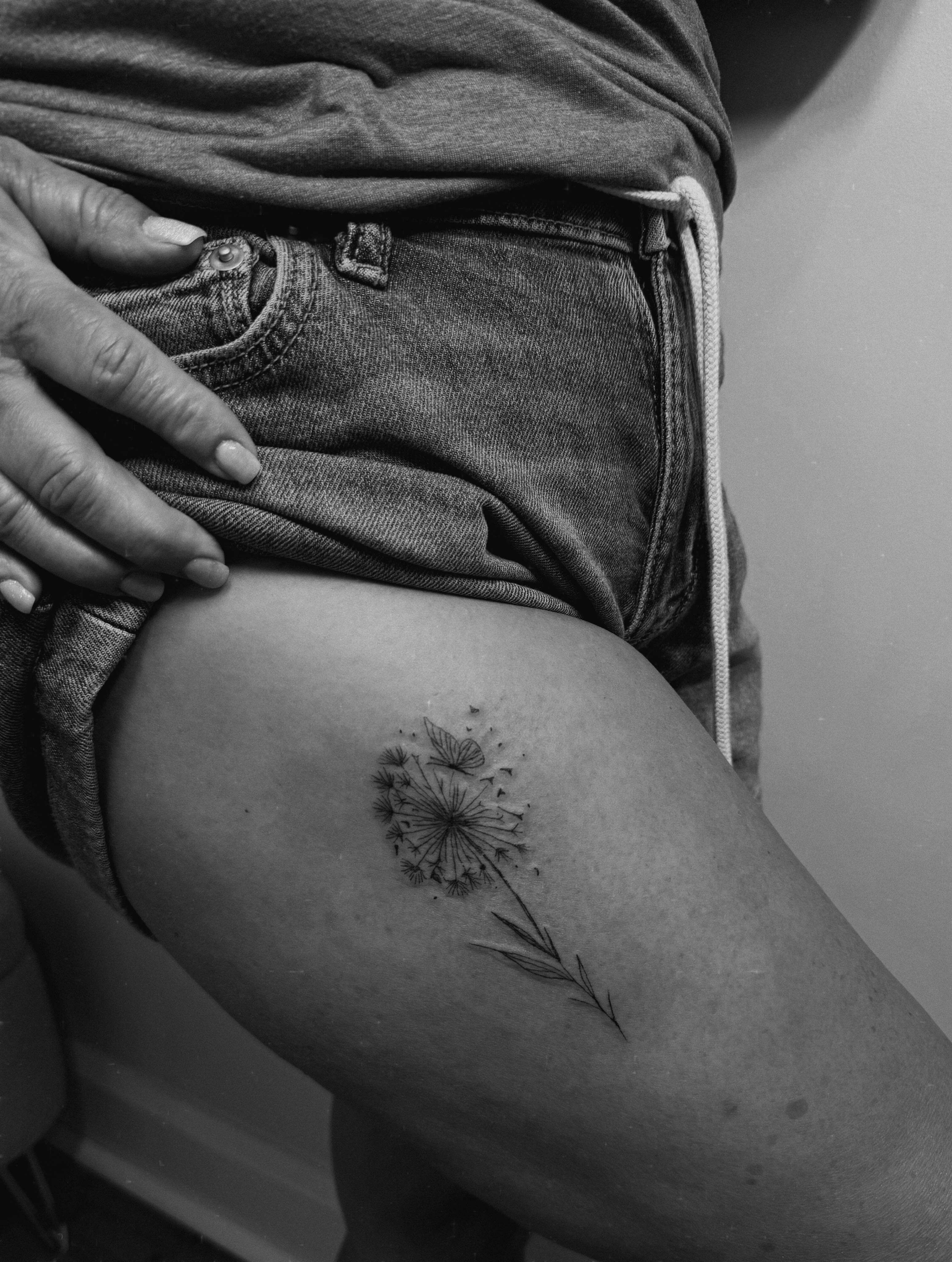 Dandelion black and grey tattoo on the thigh by Ashlee Burkey