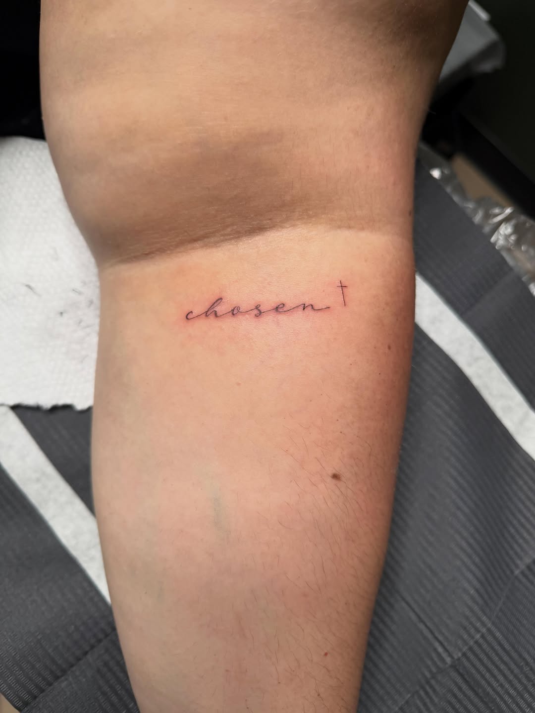 Word 'chosen' and a cross lettering tattoo on the forearm by Fineline Tattoos π€ Hailey L.
