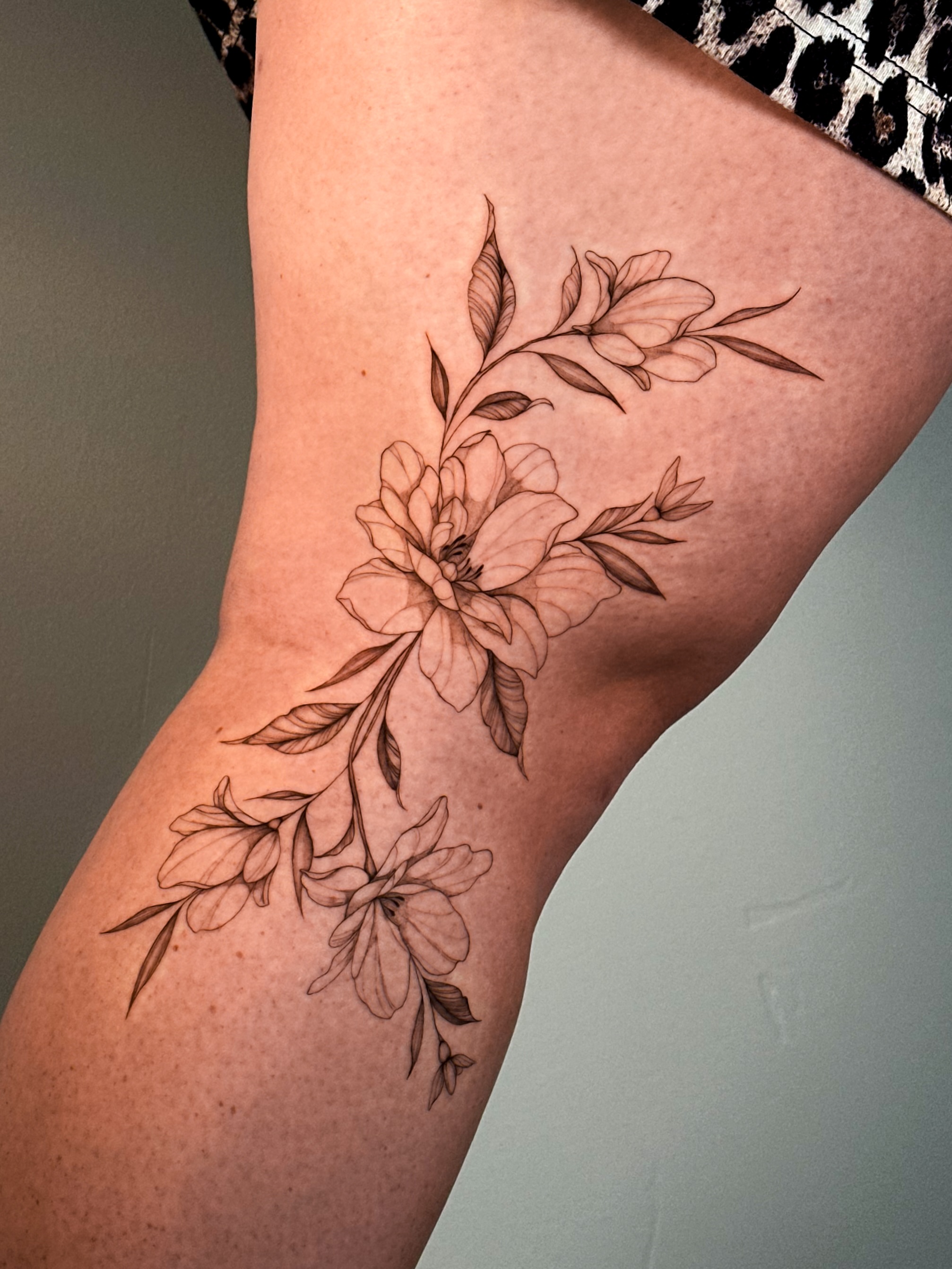 Floral arrangement black and grey tattoo on the thigh by Caroline + Utah Tattoo Artist