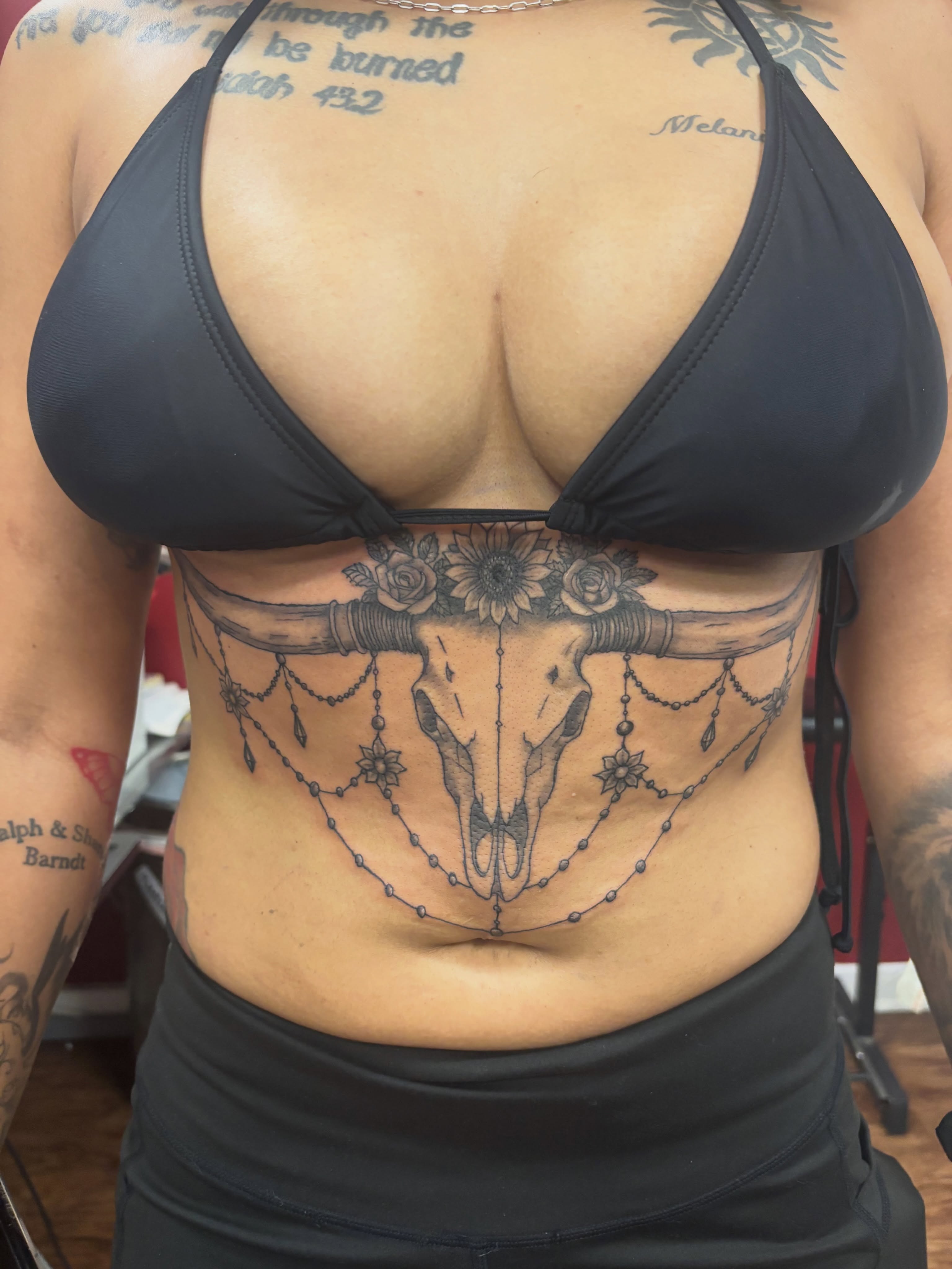 Skull with floral and beadwork ornamental tattoo on the torso by Thom Johns-Green
