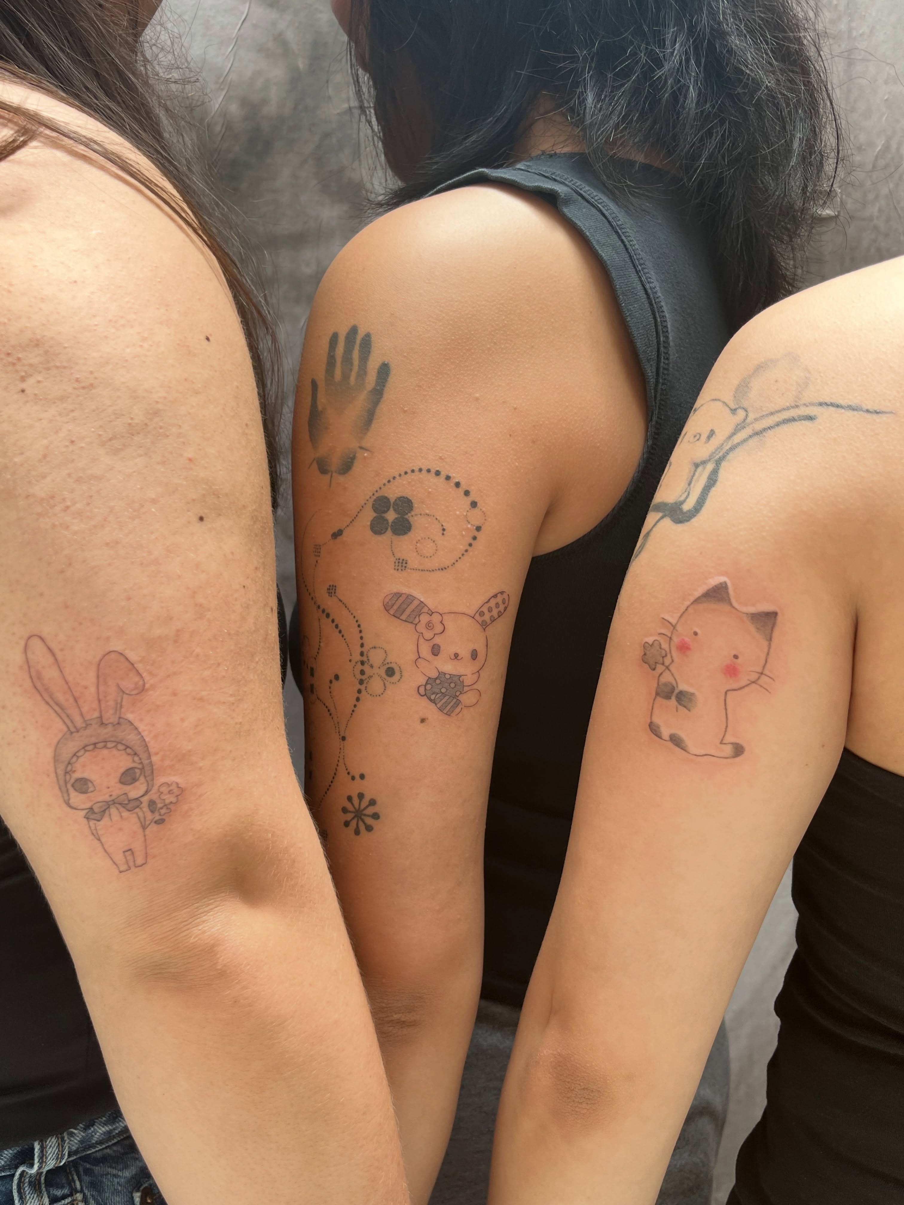 Cat and rabbit dotwork tattoo on the upper arm by Kyra Monterrosa