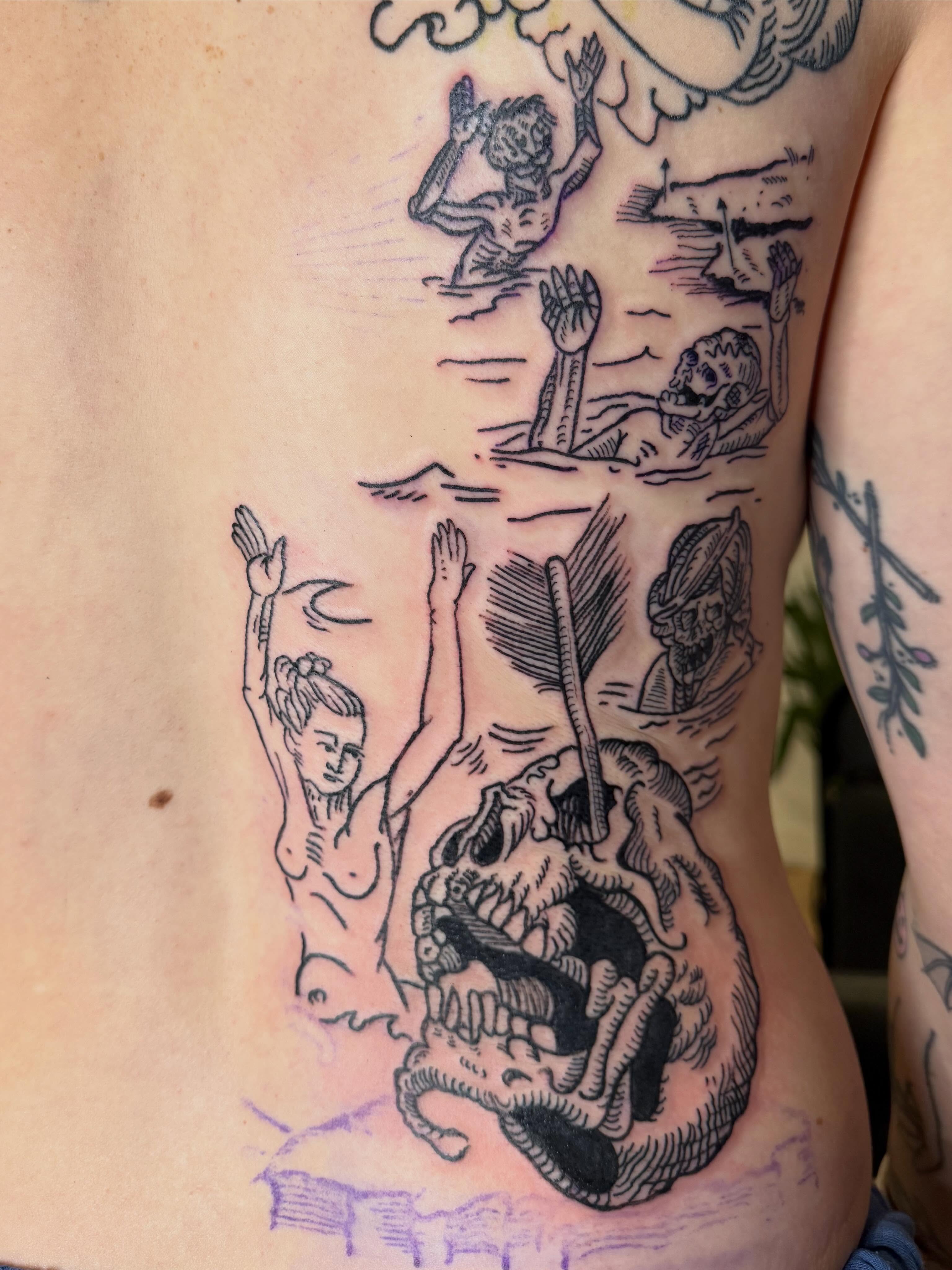 Human skull with figures American traditional tattoo on the ribs by Eric Guntor, Philadelphia, Pennsylvania