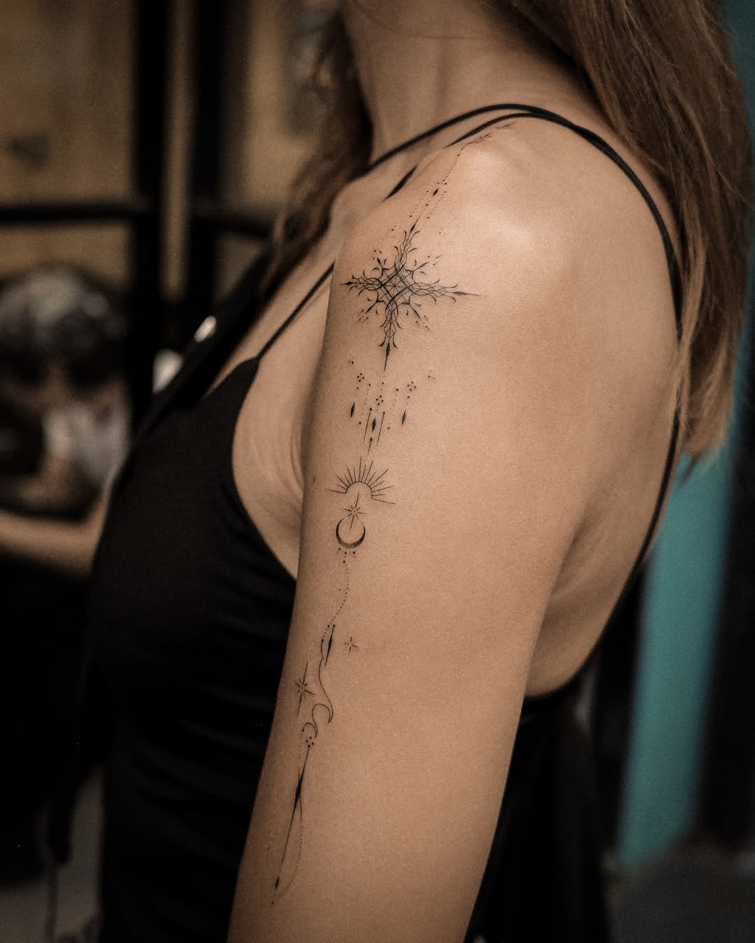 Celestial elements with starburst ornamental tattoo on the upper arm by Easy