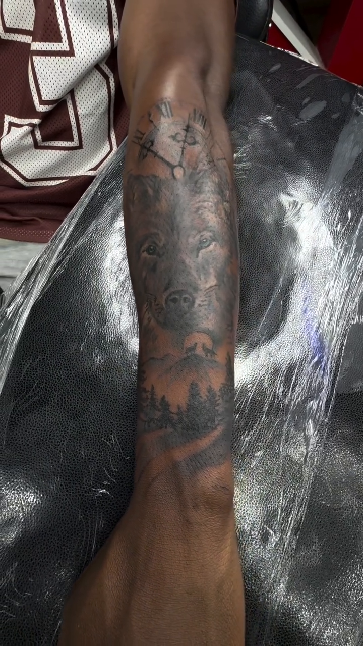 Wolf and forest scene with clock realism tattoo on the upper arm by Art Plug