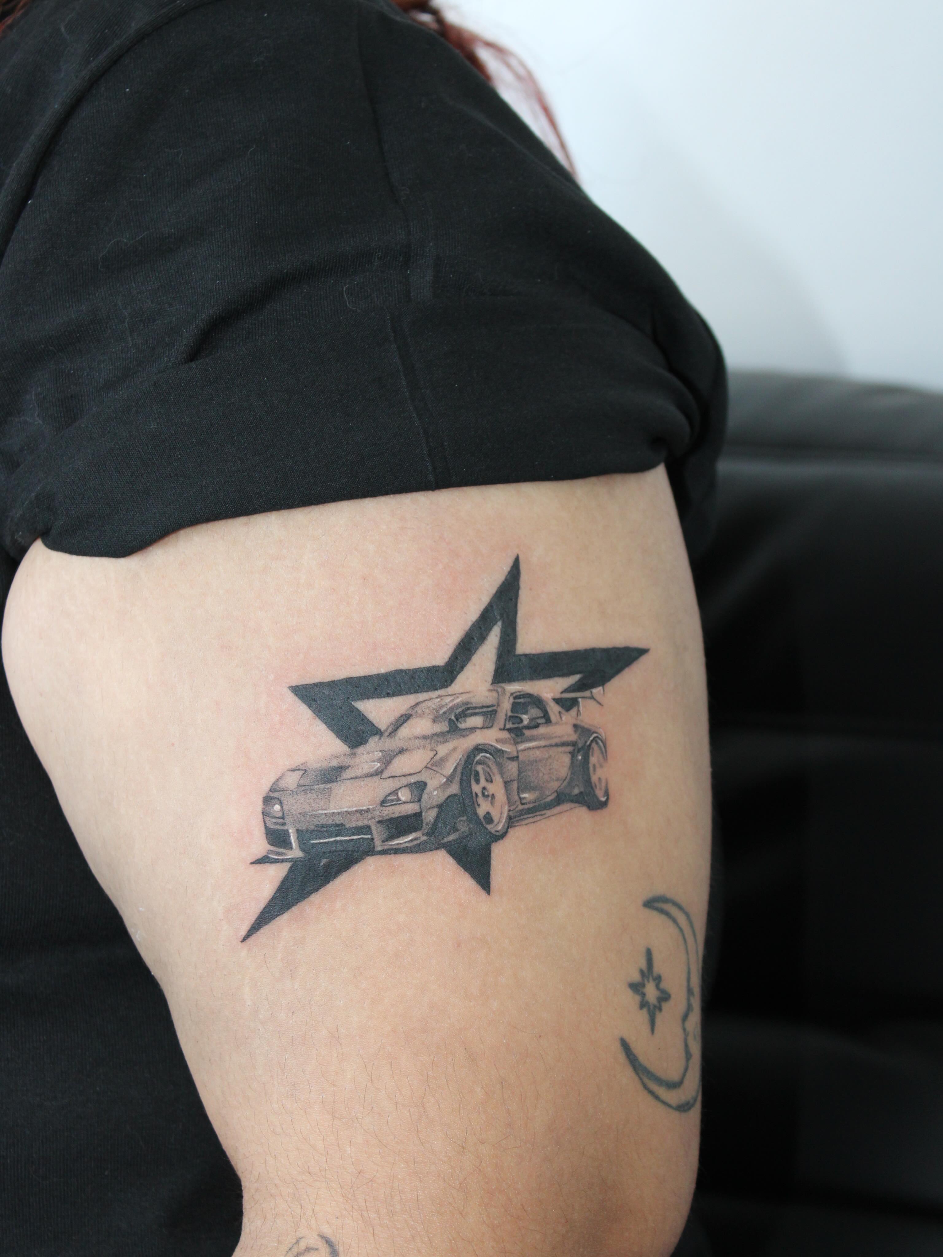 Car and star black and grey tattoo on the forearm by Julianna