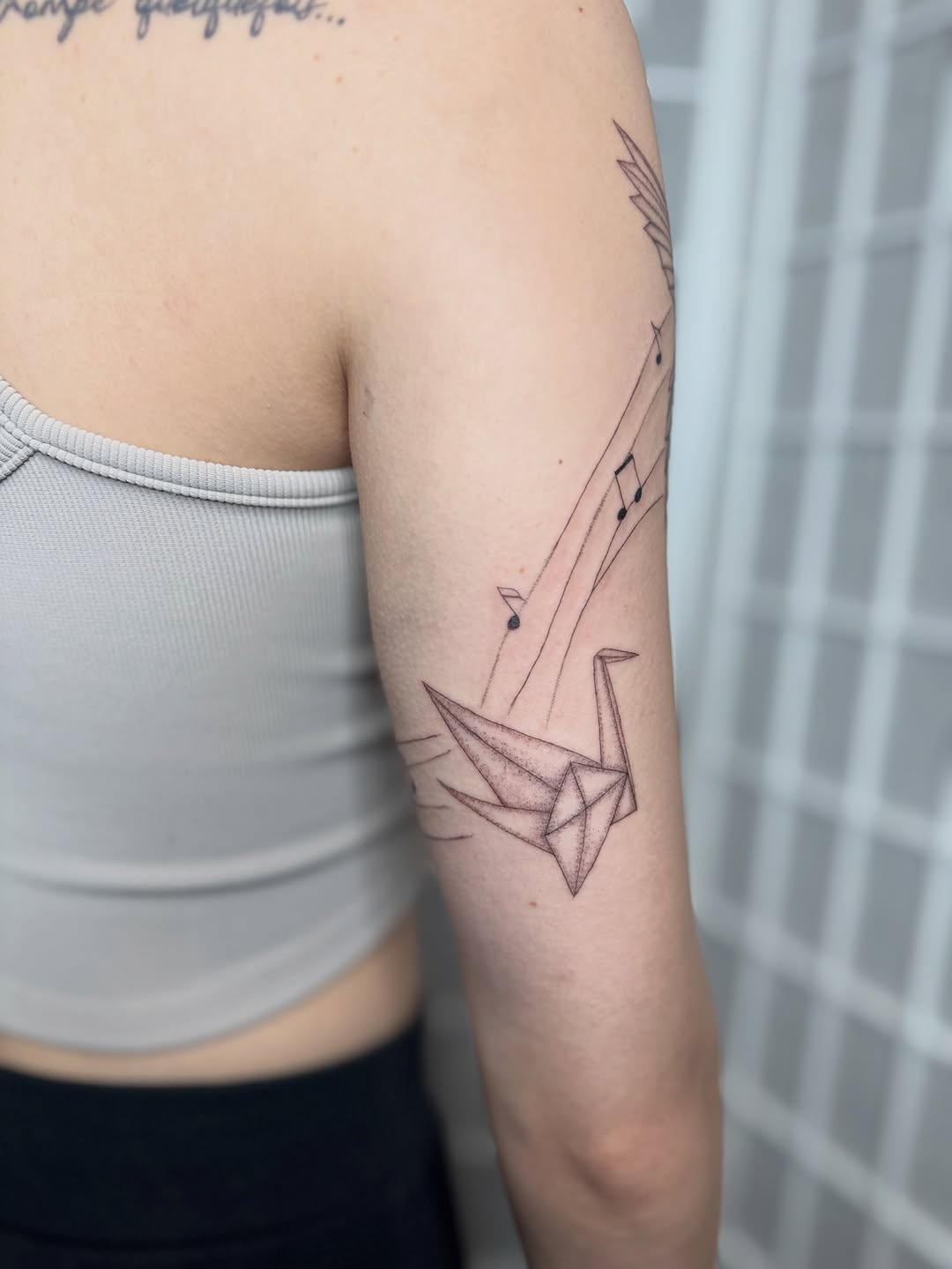 Origami crane with musical notes minimalist tattoo on the forearm by Dama
