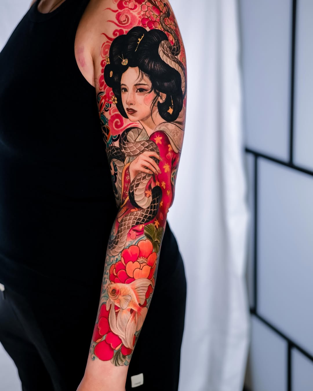 Geisha with snake and goldfish Japanese tattoo on the upper arm by Andres Acevedo, Denver, Colorado
