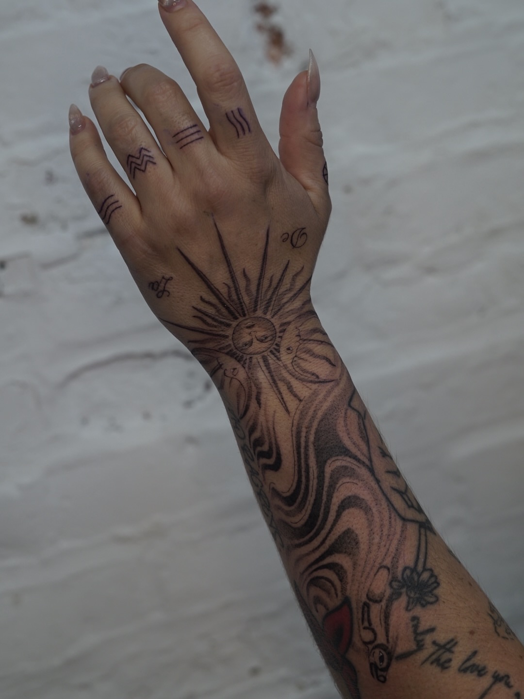 Sun and floral black and grey tattoo on the forearm by Josh Infante