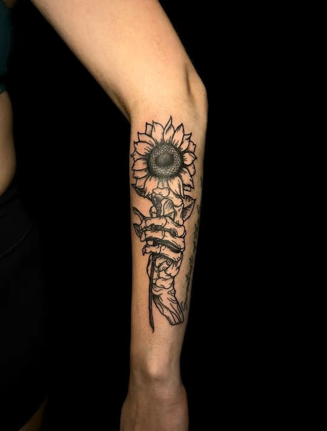 Skeleton hand holding a sunflower sketch tattoo on the forearm by JT.tattoos